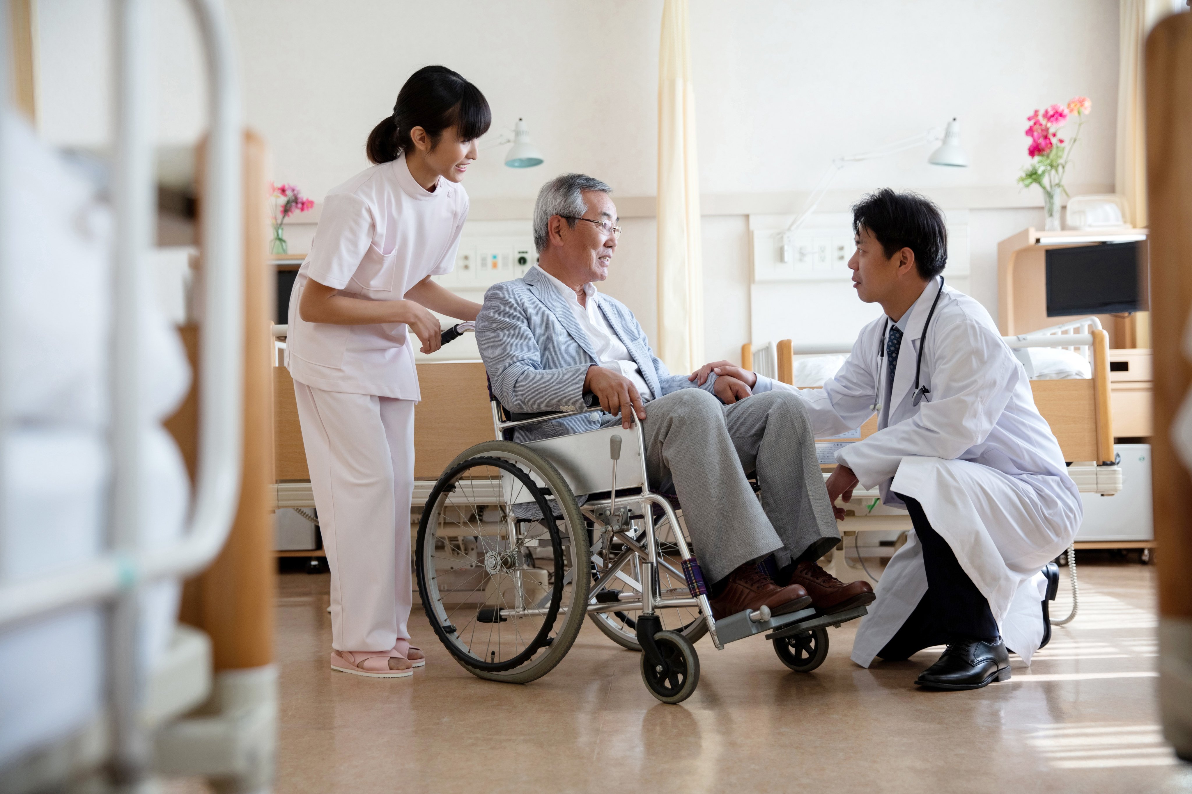A doctor discussing with a senior man sitting in a wheelchair in a hospital ward in Tokyo, Japan. Photo: Getty Images
