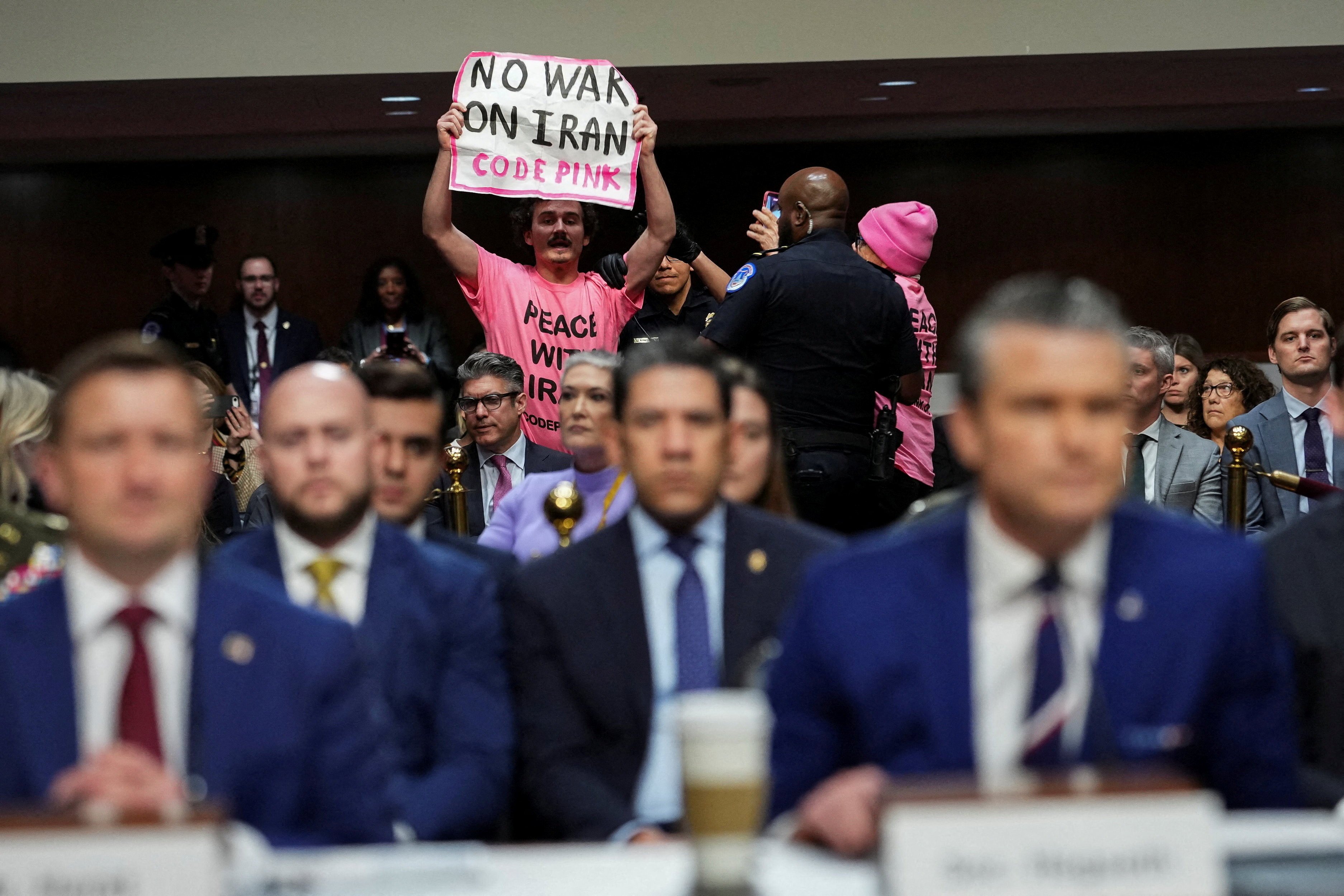 A protester holds a banner opposing the war with Iran during US Defence Secretary Pete Hegseth’s testimony in the Senate on Thursday. Photo: Reuters