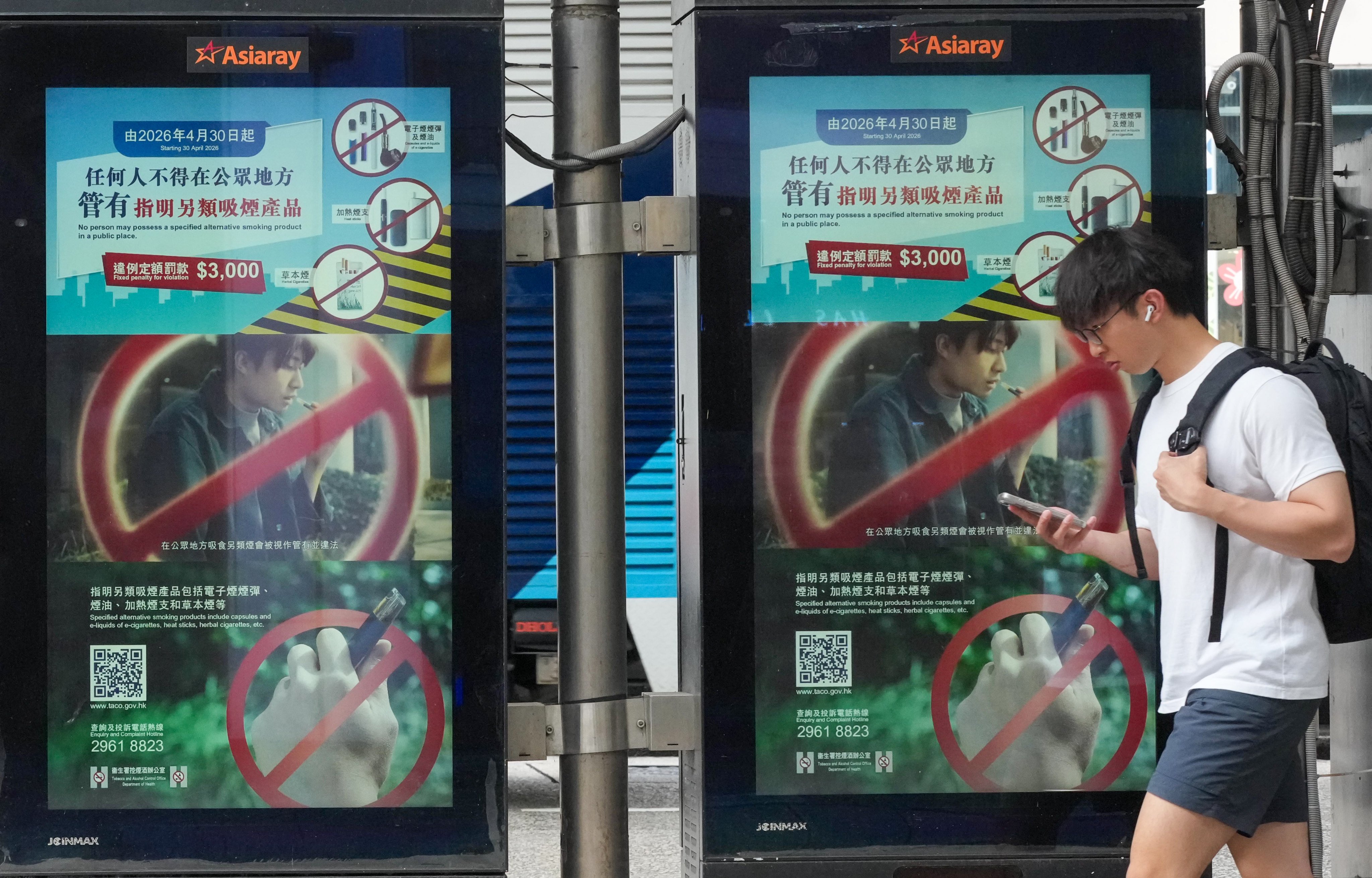 A pedestrian walks past at a bus stop in Tsim Sha Tsui with an advertisement promoting the ban on the public use of alternative smoking products, on April 28. Photo: Jelly Tse