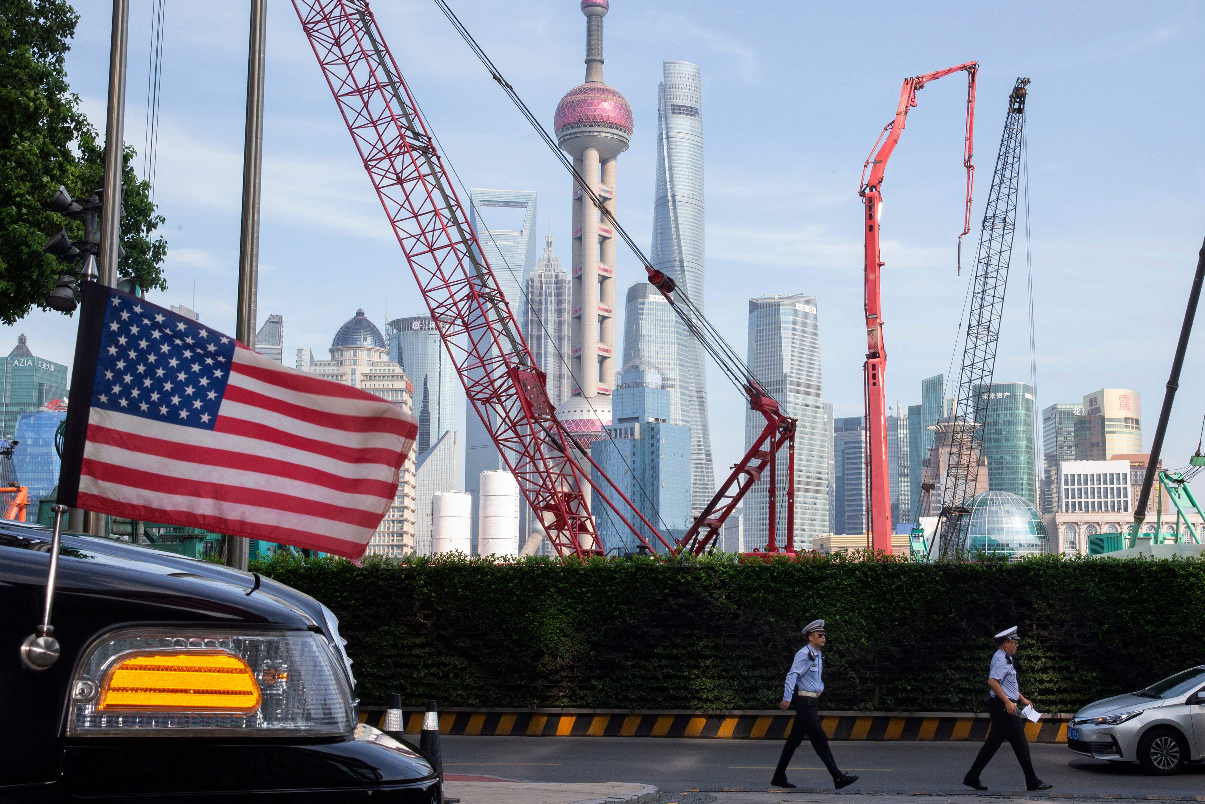 Chinese traffic police officers walk by a US flag on an embassy car outside a hotel in Shanghai on July 30, 2019, as officials from both sides met for talks aimed at ending a tariff war. Photo: AP