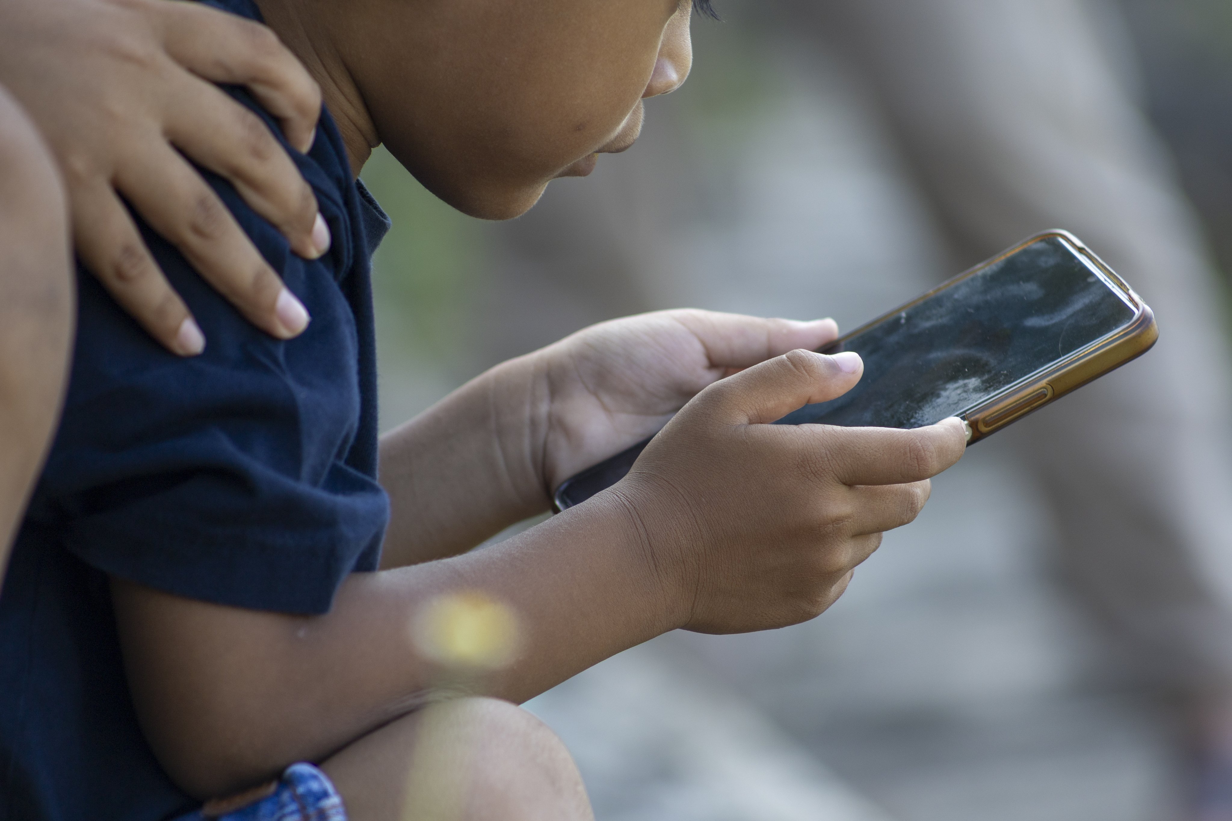 A child uses a mobile phone at a park in Denpasar, Bali on March 28, when the Indonesian government began implementing a social media ban for children under 16. The Hong Kong government has not introduced such a ban, but might consider other measures to protect children. Photo: EPA