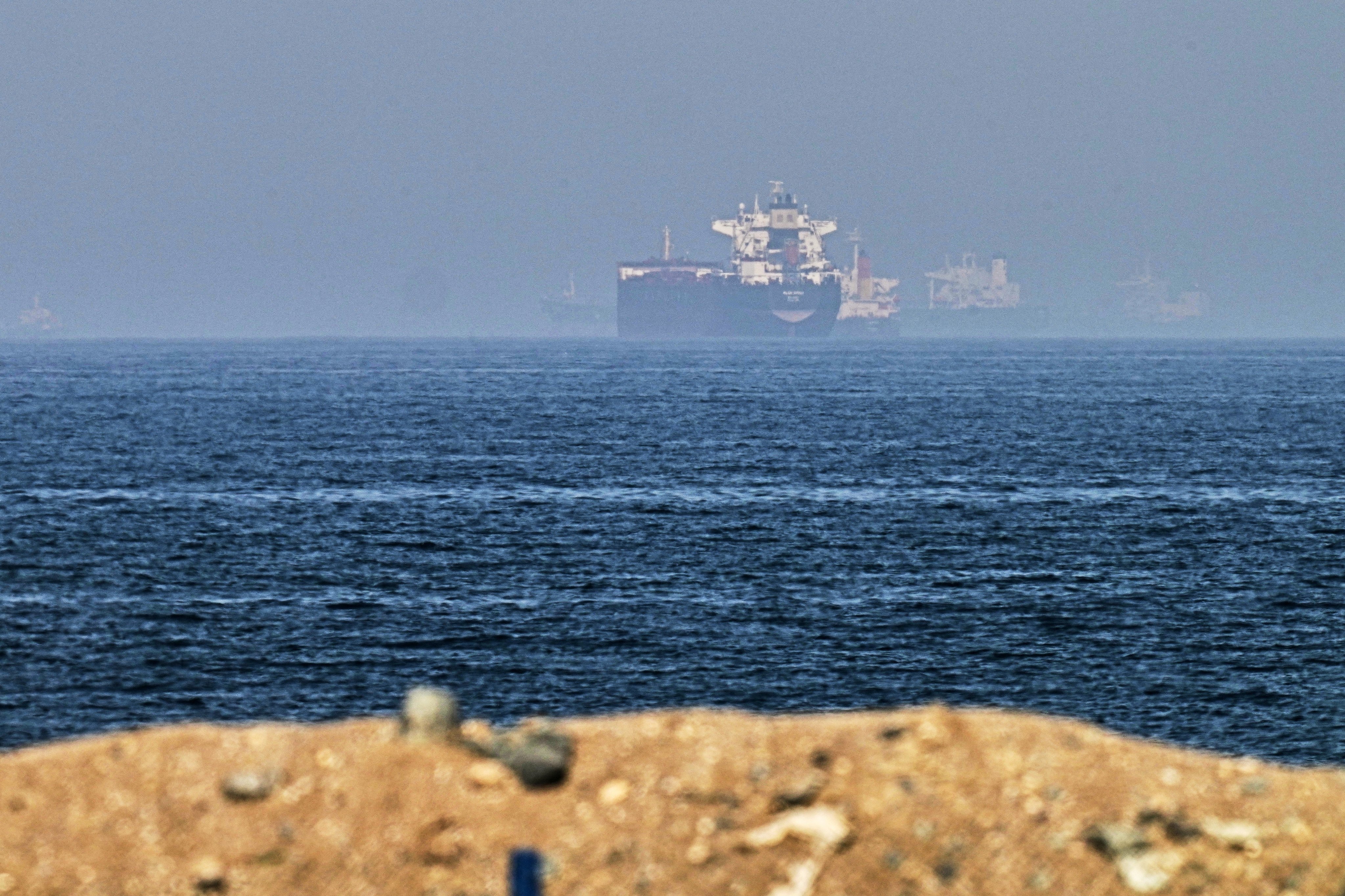 Cargo ships near the Strait of Hormuz, viewed from a rocky shoreline near Khor Fakkan, United Arab Emirates on Friday. On Sunday, an unidentified carrier in the strait reported being attacked by multiple small craft. Photo: AP