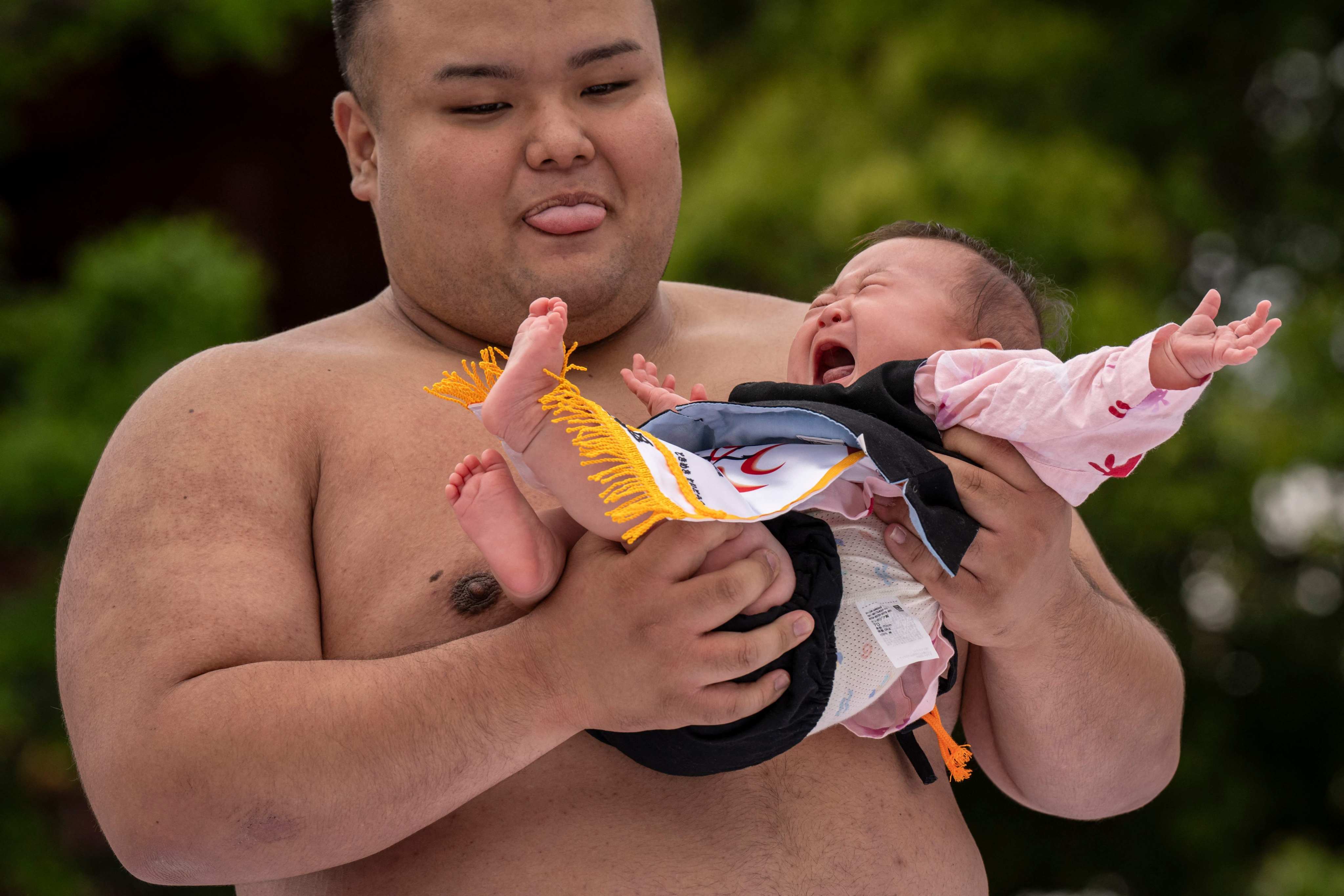 A sumo wrestler holds a child during the crying baby sumo match at Sensoji temple in Tokyo. Photo: AFP