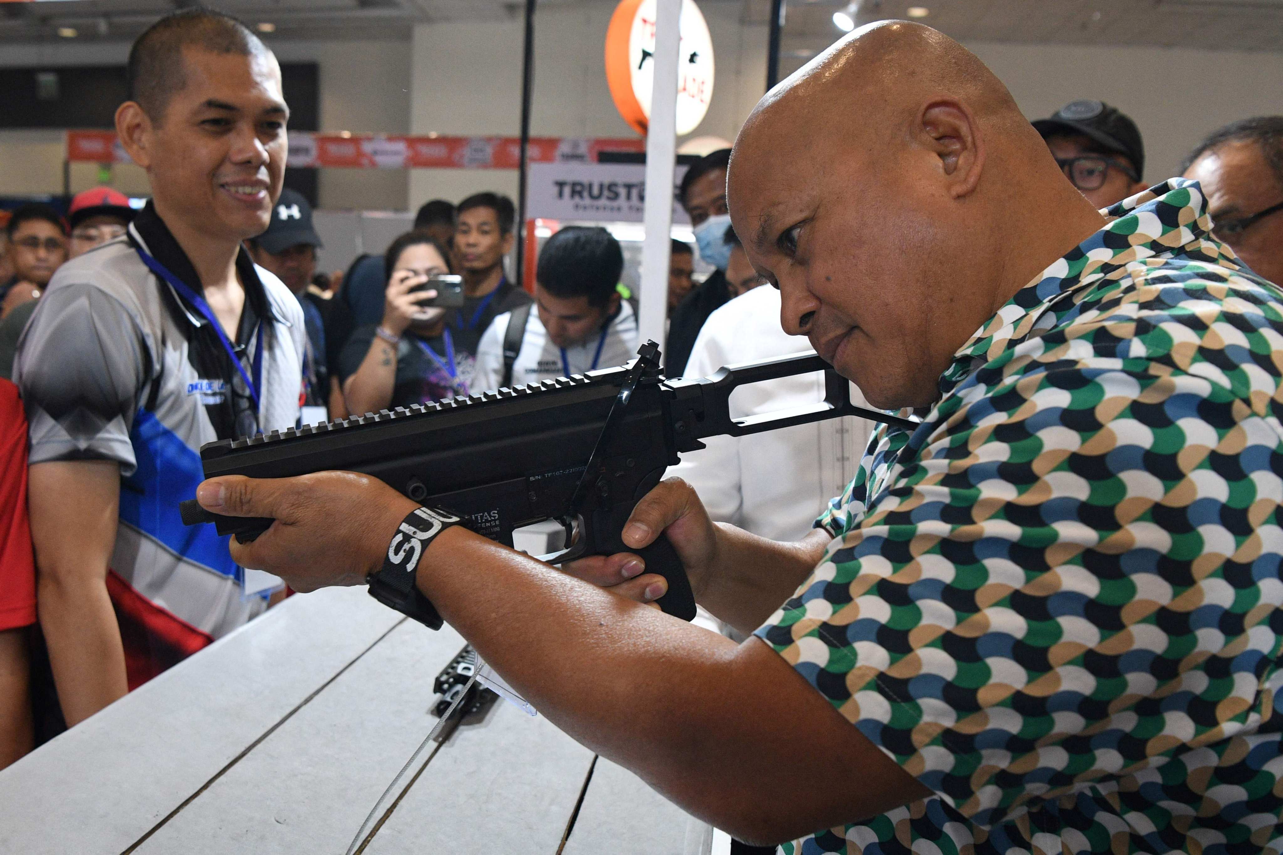 Philippine former national police chief and now Senator Ronald Dela Rosa tries a semi-automatic rifle during a defence and sporting show in Pasay City in 2023. Photo: AFP