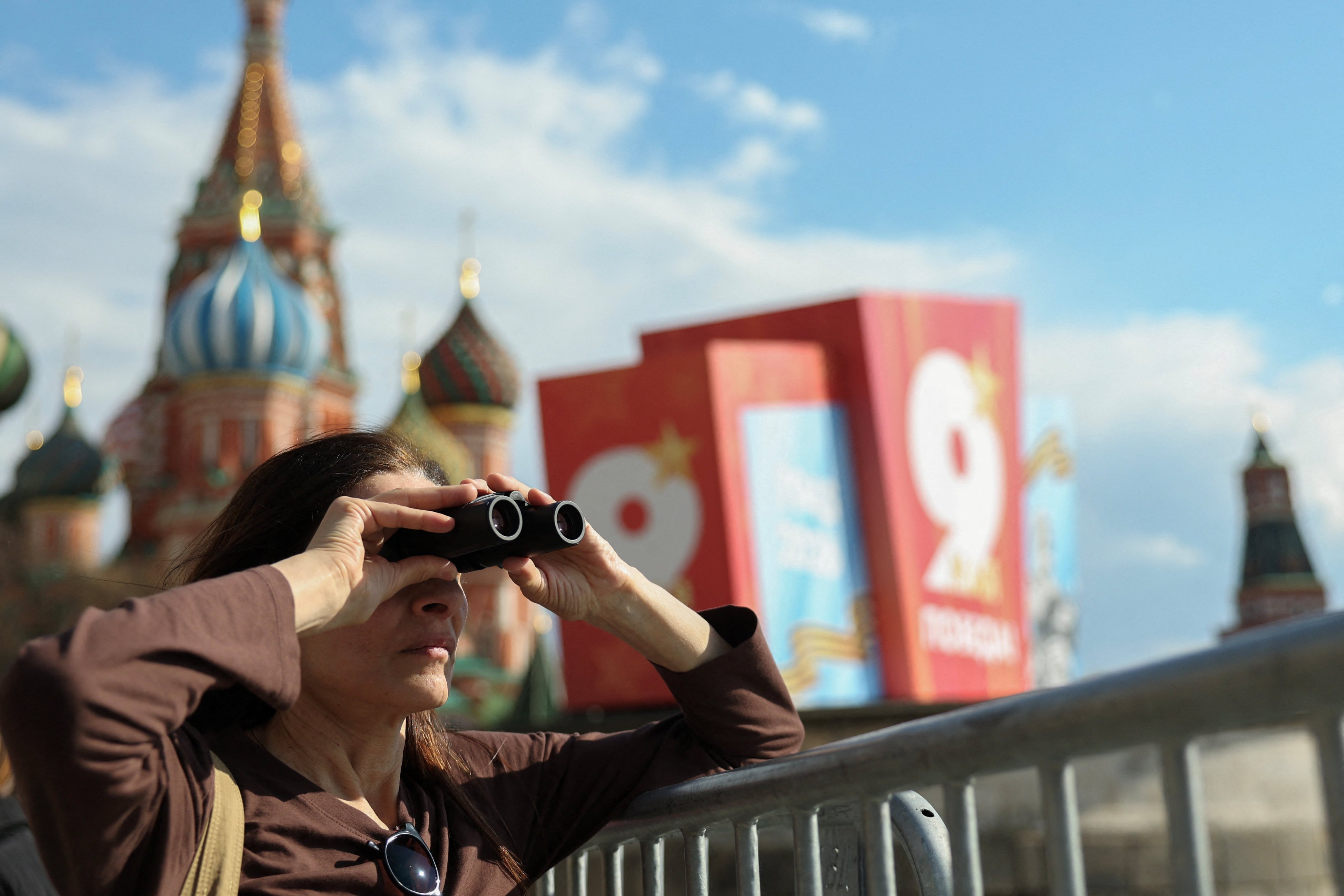 A tourist looks through binoculars at Red Square in Moscow. Photo: Reuters