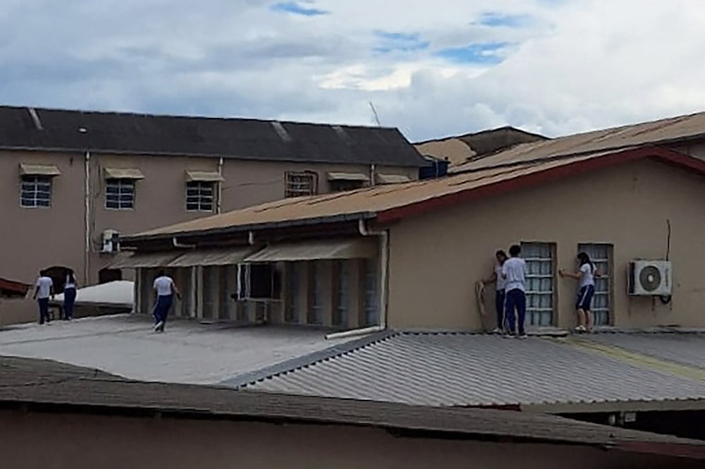 Students at Sao Jose Institute in Rio Branco take cover on the roof while during a shooting incident on Tuesday. Photo: AFP