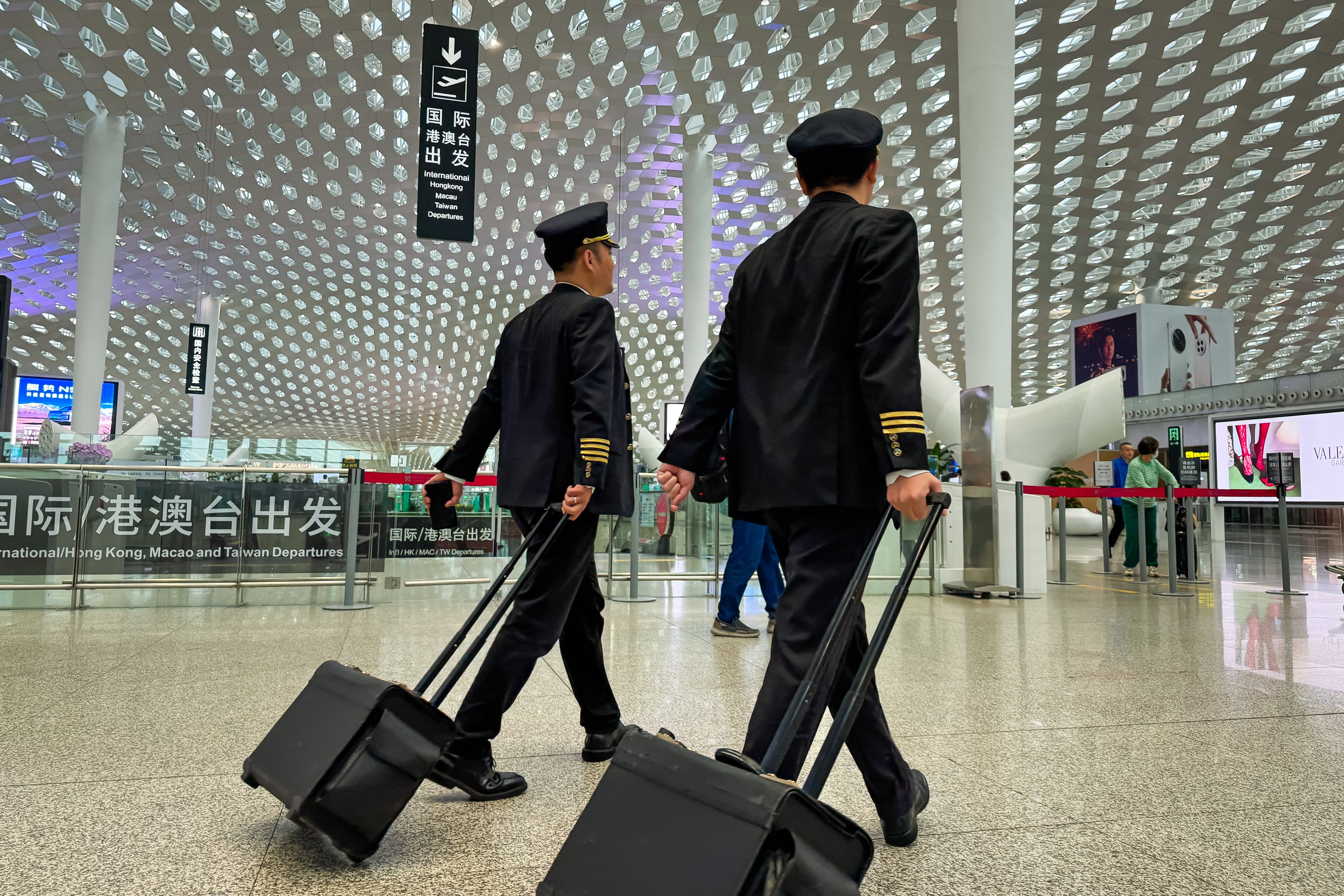 Two commercial airline pilots walk through the departure hall of Shenzhen Bao’an International Airport, as foreign pilots seeking to launch a career in China are warned of stiff competition and rigid standards. Photo: Getty