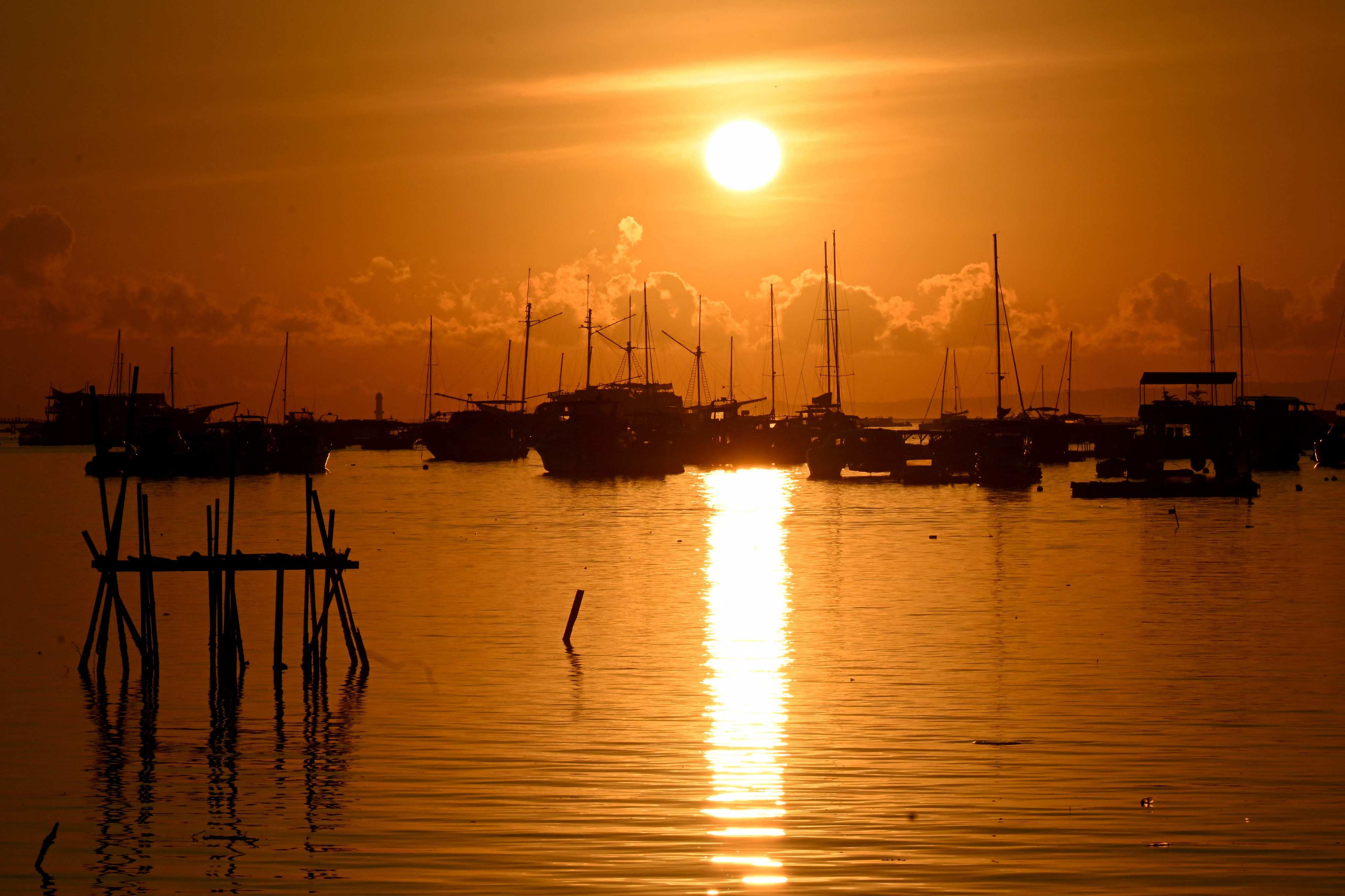 The sun rises behind boats moored at a pier near Denpasar on Indonesia’s resort island of Bali on April 12. Photo: AFP