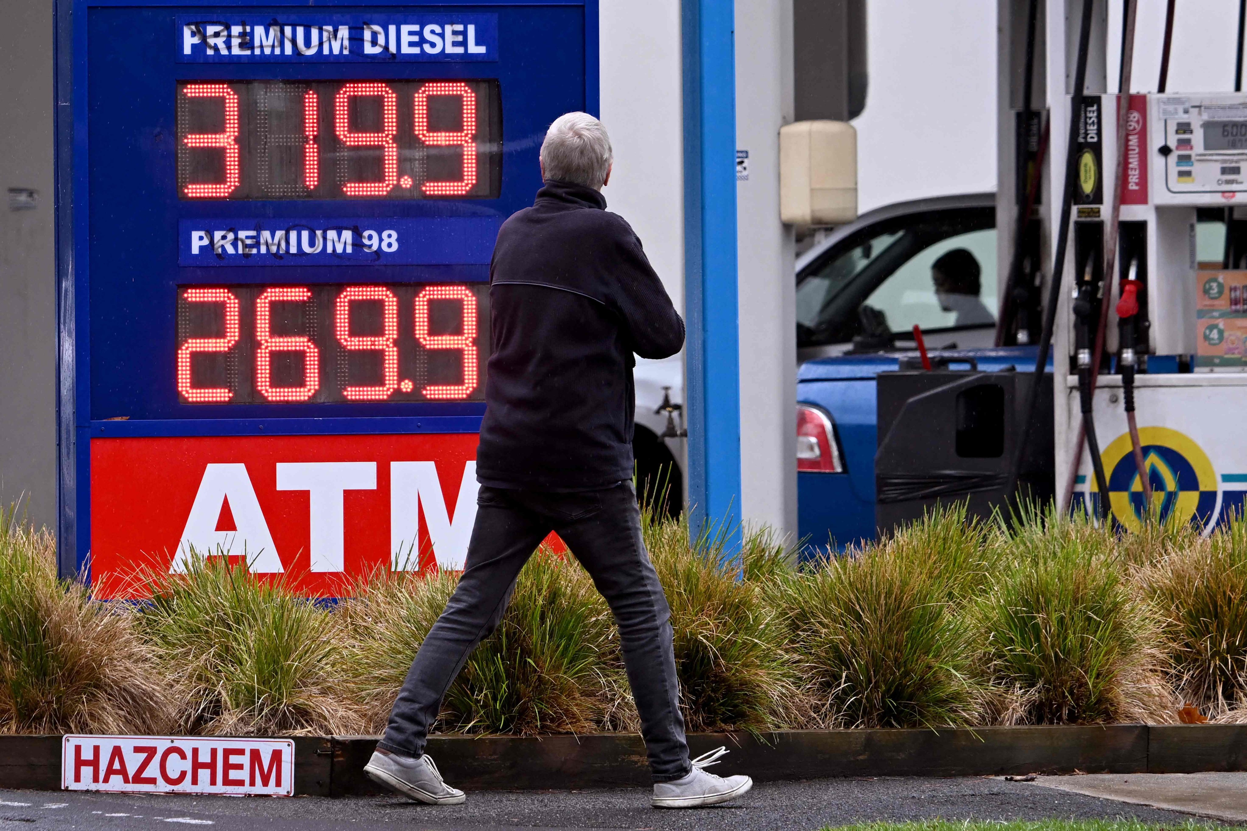 A pedestrian walks past a petrol station with fuel prices on display in  Williamstown, Australia, on March 26. Photo: AFP