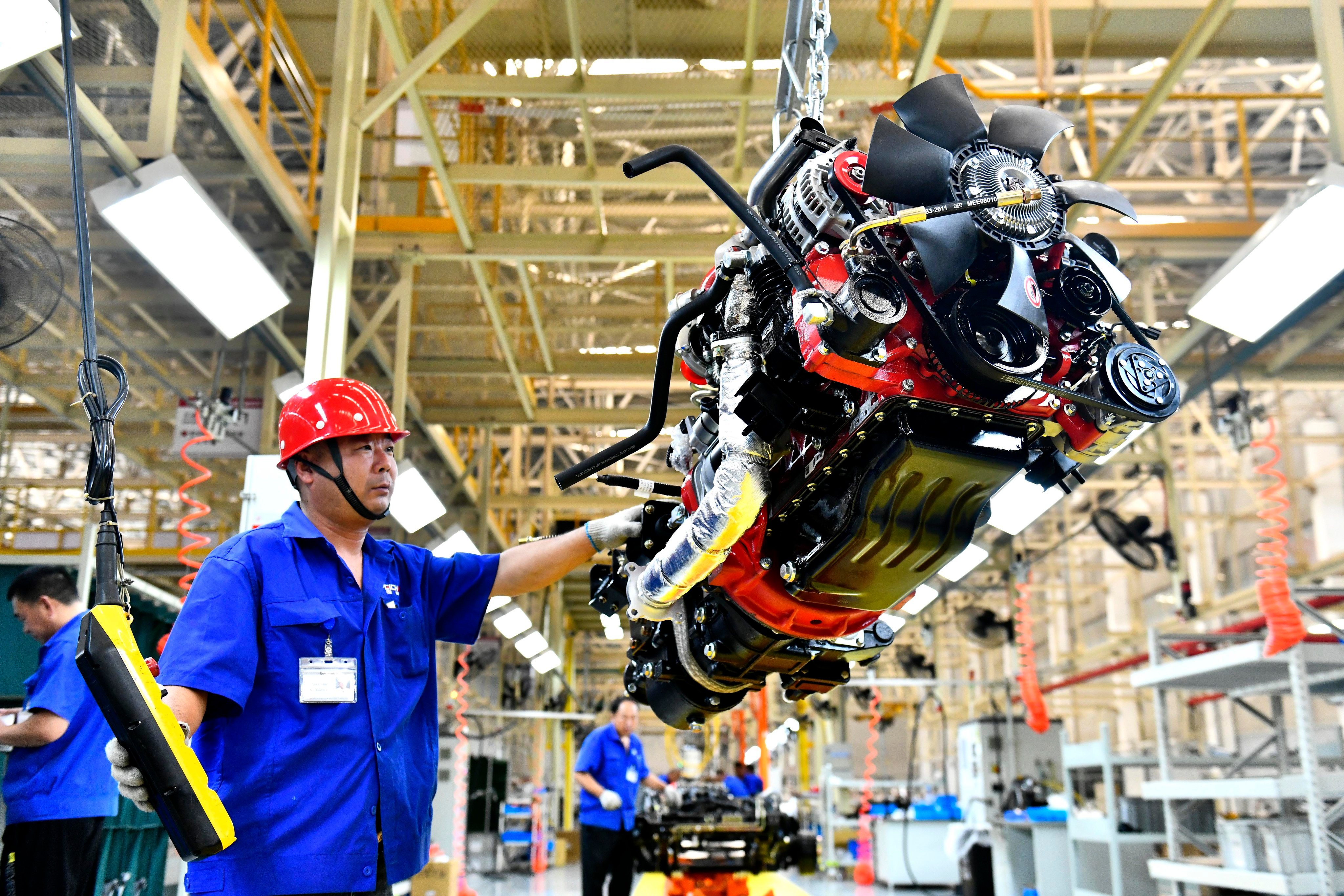 A worker lifts an engine at the production line of Weichai New Energy Commercial Vehicle in Weihai city, eastern China. Photo: EPA-EFE/Xinhua