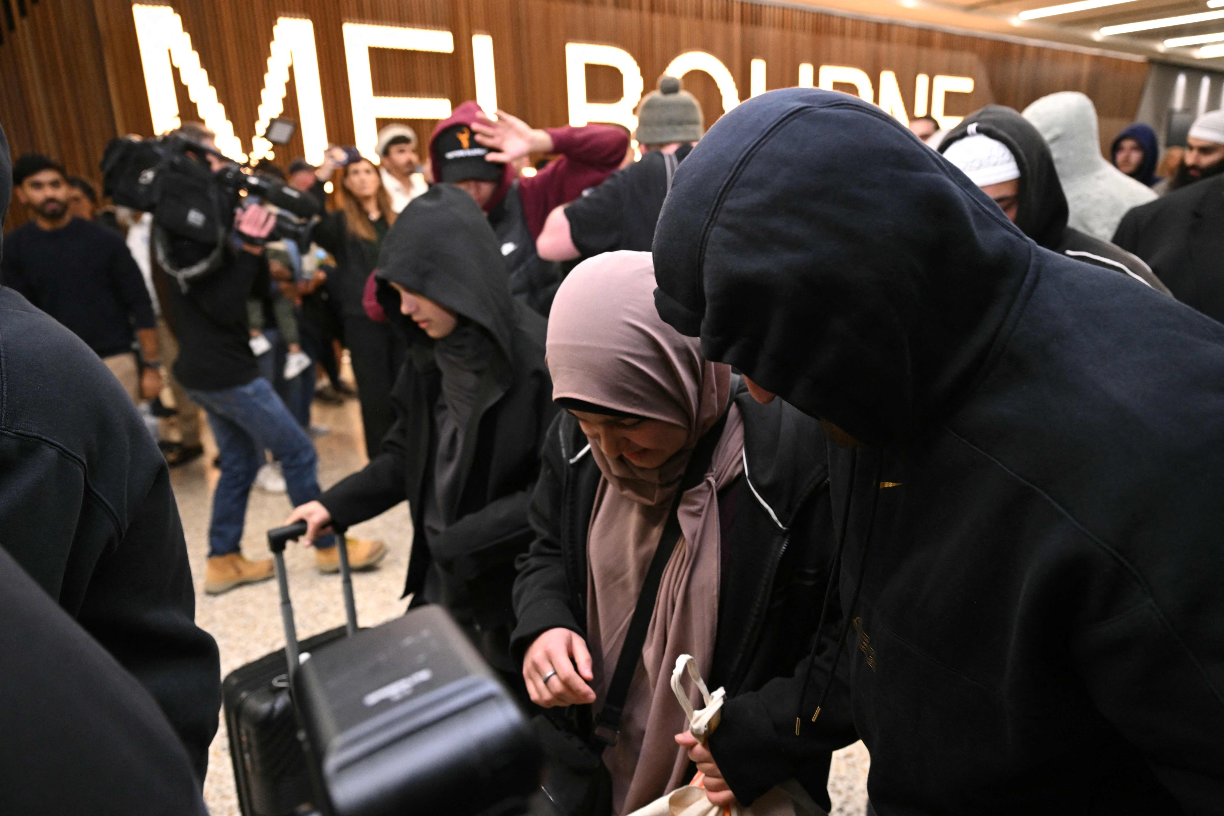 Australian women returning from Syrian refugee camps where they have been staying since Islamic State’s demise walk past the media as they arrive at the airport in Melbourne on Thursday. Photo: AFP