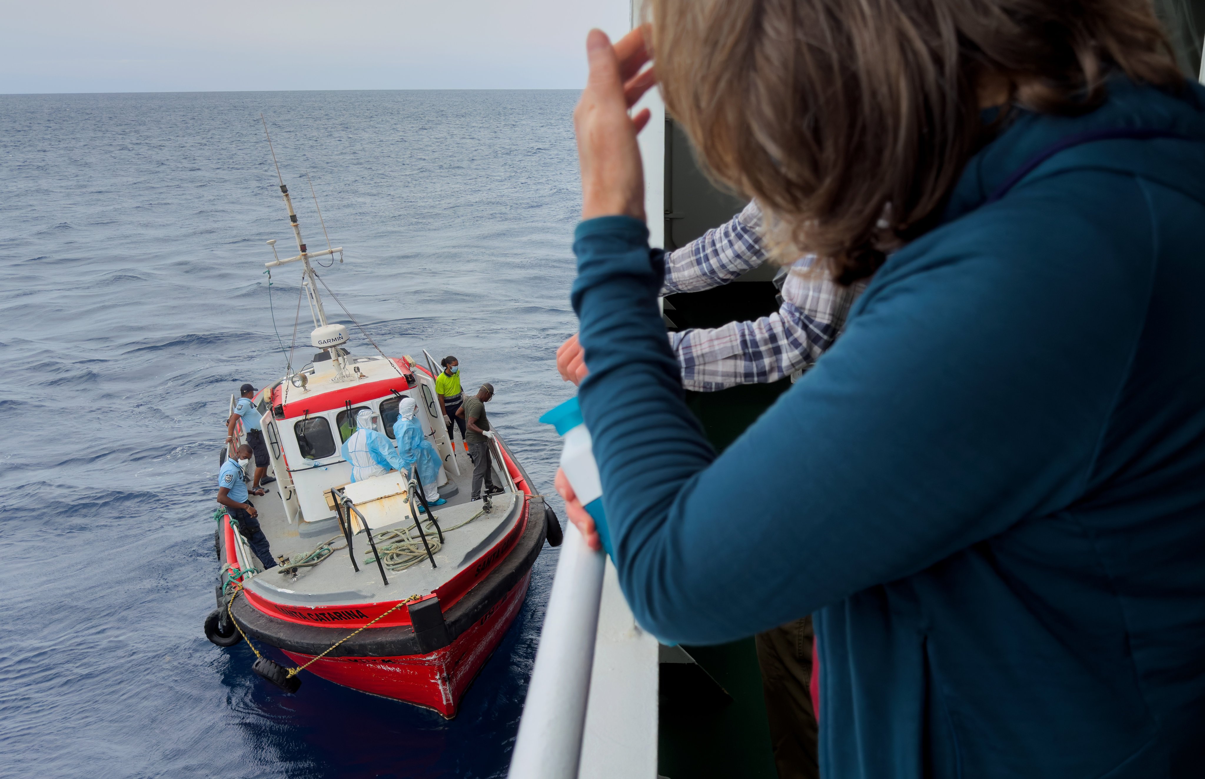 Passengers on the the hantavirus-stricken cruise ship MV Hondius watch epidemiologists prepare to board off the coast of Africa. Photo: AP