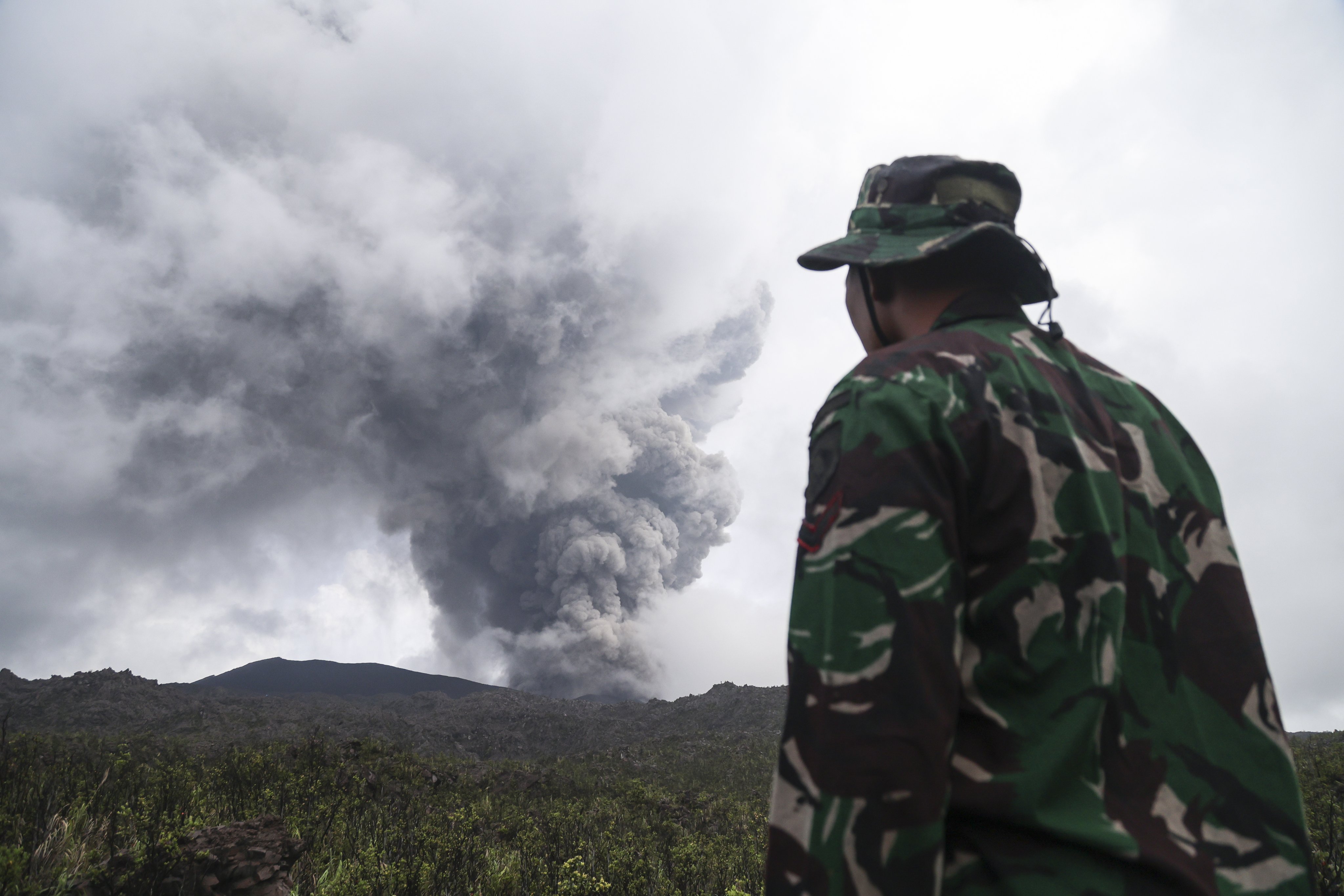 A rescuer looks at Mount Dukono volcano during its eruption in North Halmahera, Indonesia, on Saturday. Photo: EPA