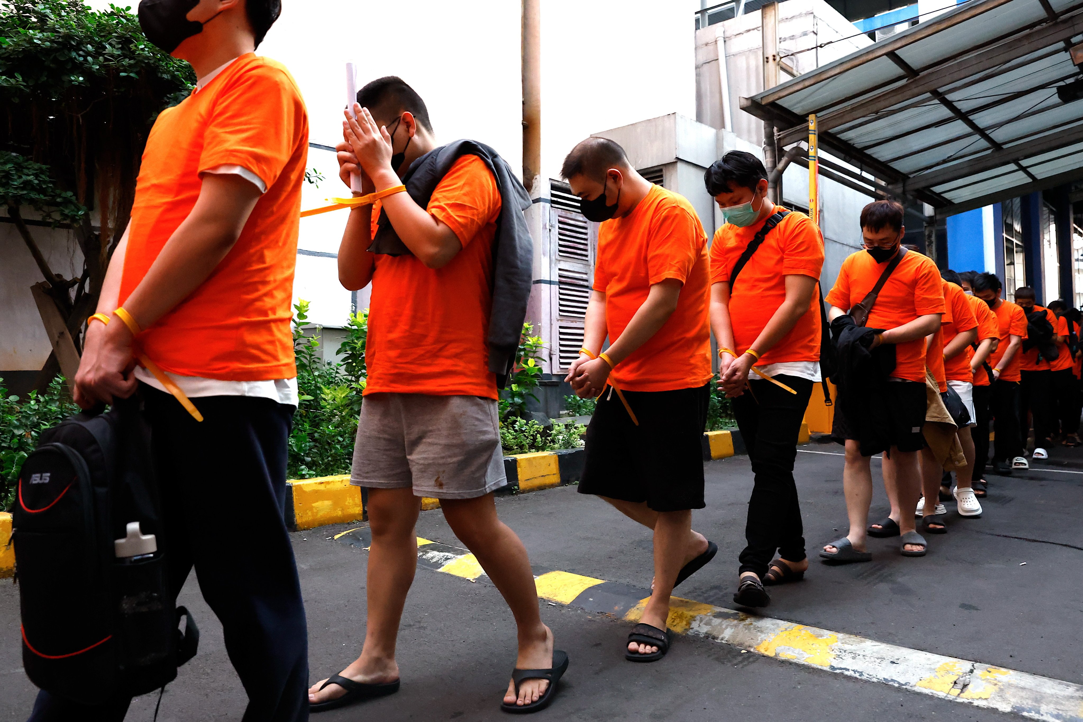 Police officers escort suspects out of an office building during a raid on an illegal gambling operation in Jakarta, Indonesia, on Sunday. Photo: EPA-EFE