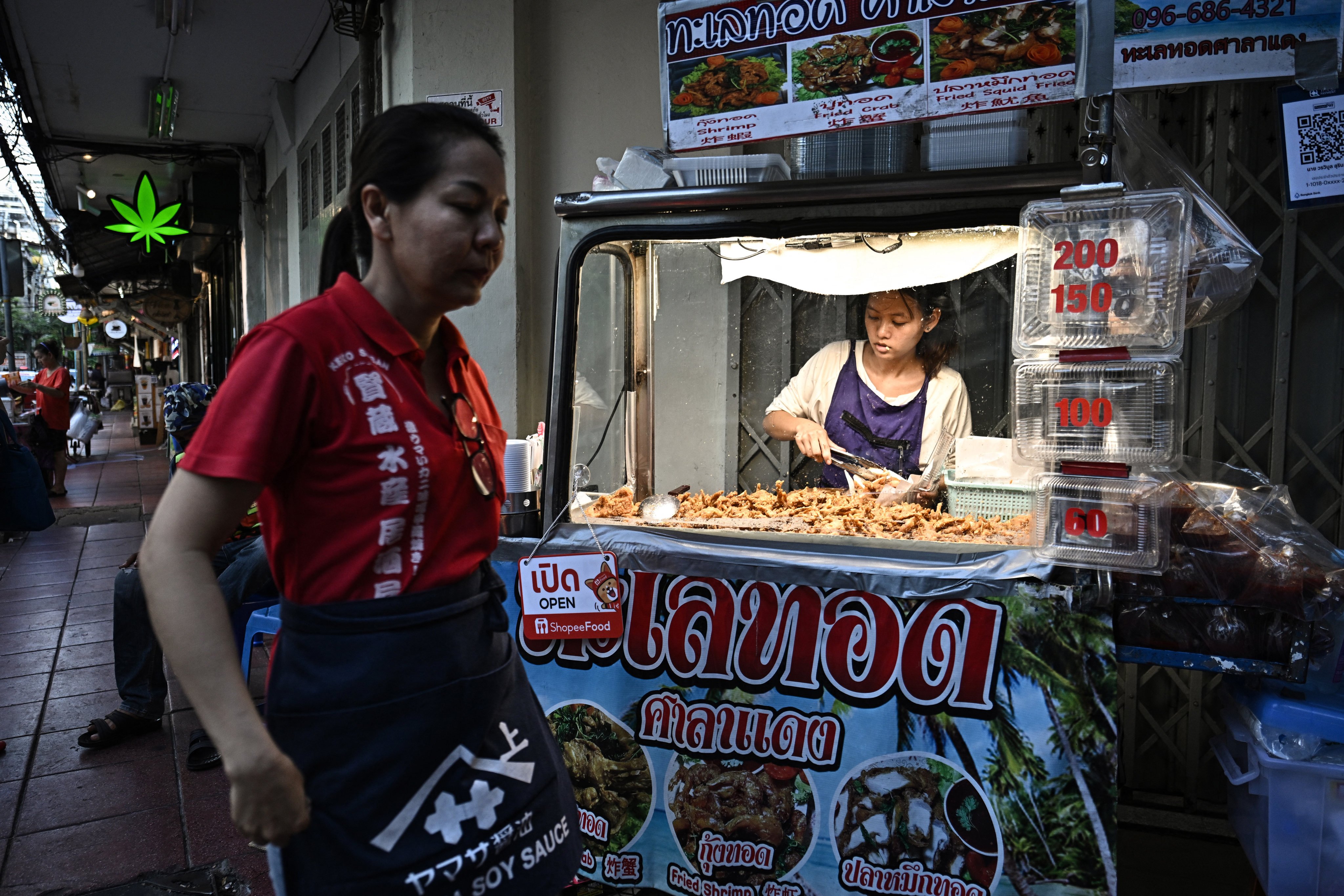 This photo taken on April 30, 2026 shows a street vendor selling fried seafood along Silom road in Bangkok. Across Bangkok, aromas of garlic, chilli and grilled meat drift from roadside stalls and carts, but tighter controls on vendors threaten livelihoods and the street food culture that defines the Thai capital. (Photo by Lillian SUWANRUMPHA / AFP) / To go with AFP story Thailand-Bangkok-food-culture-economy,FOCUS by Montira Rungjirajittranon