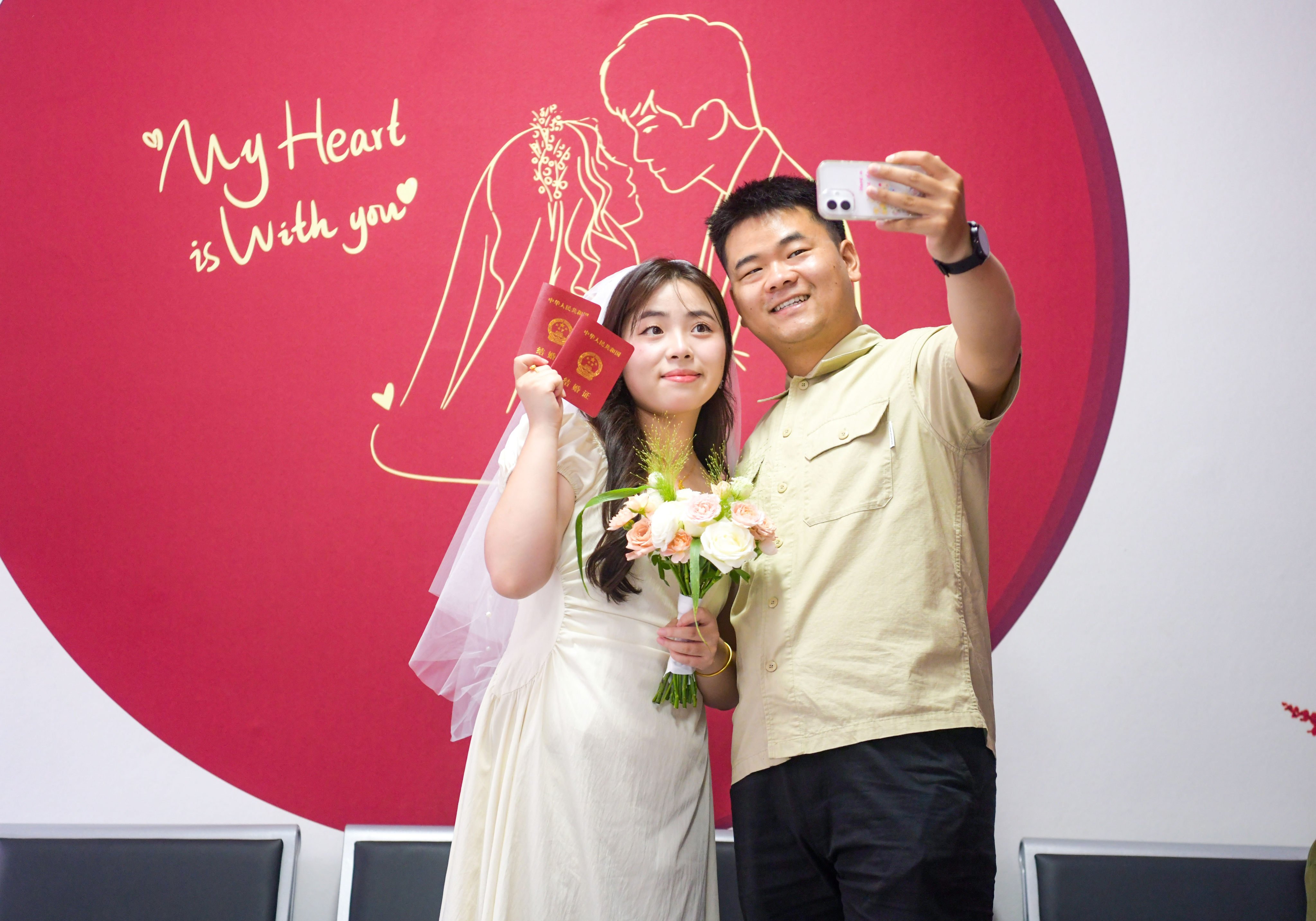 A newlywed couple takes a selfie with their marriage certificates at a marriage registration office in China’s northern Henan province. Photo: Getty Images