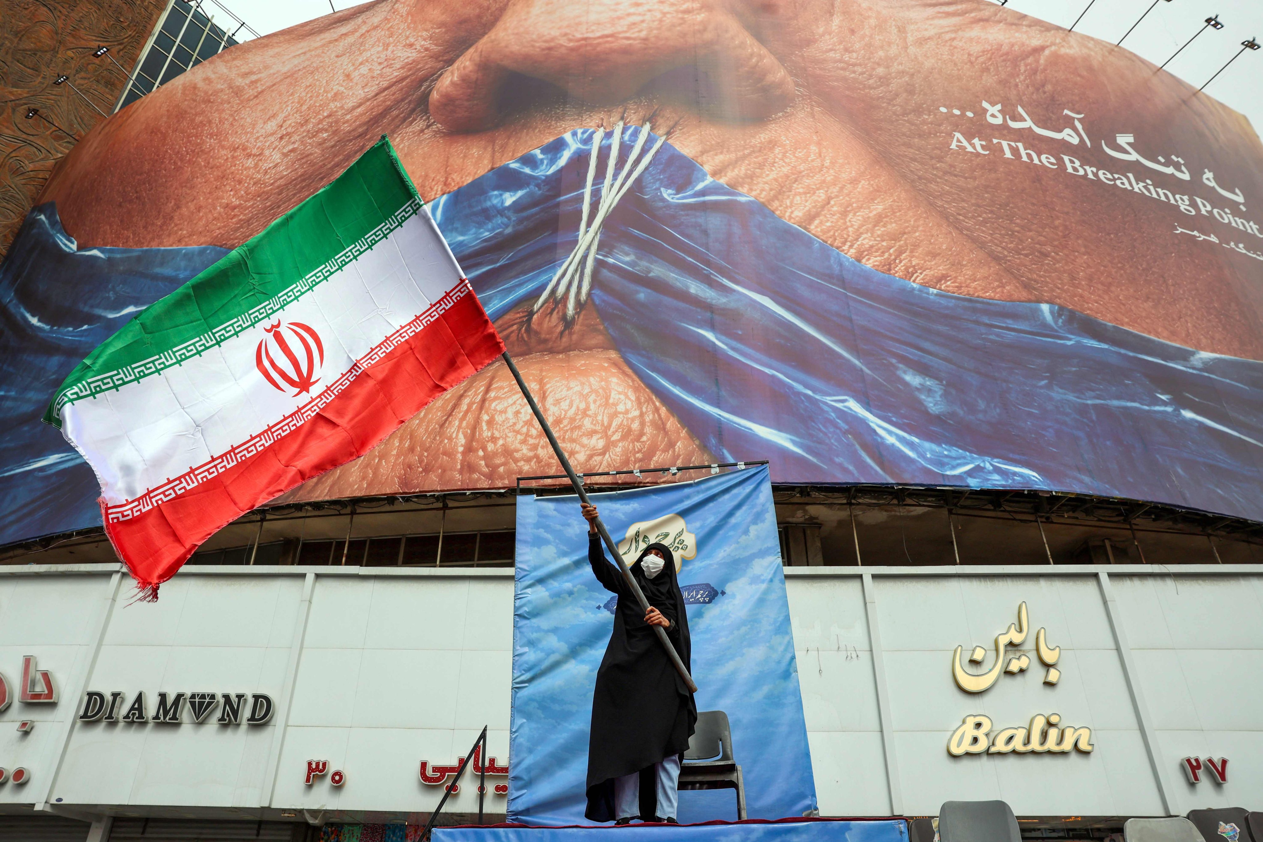 A woman waves an Iranian flag in front of an anti-US billboard in Tehran on Tuesday. Photo: AFP