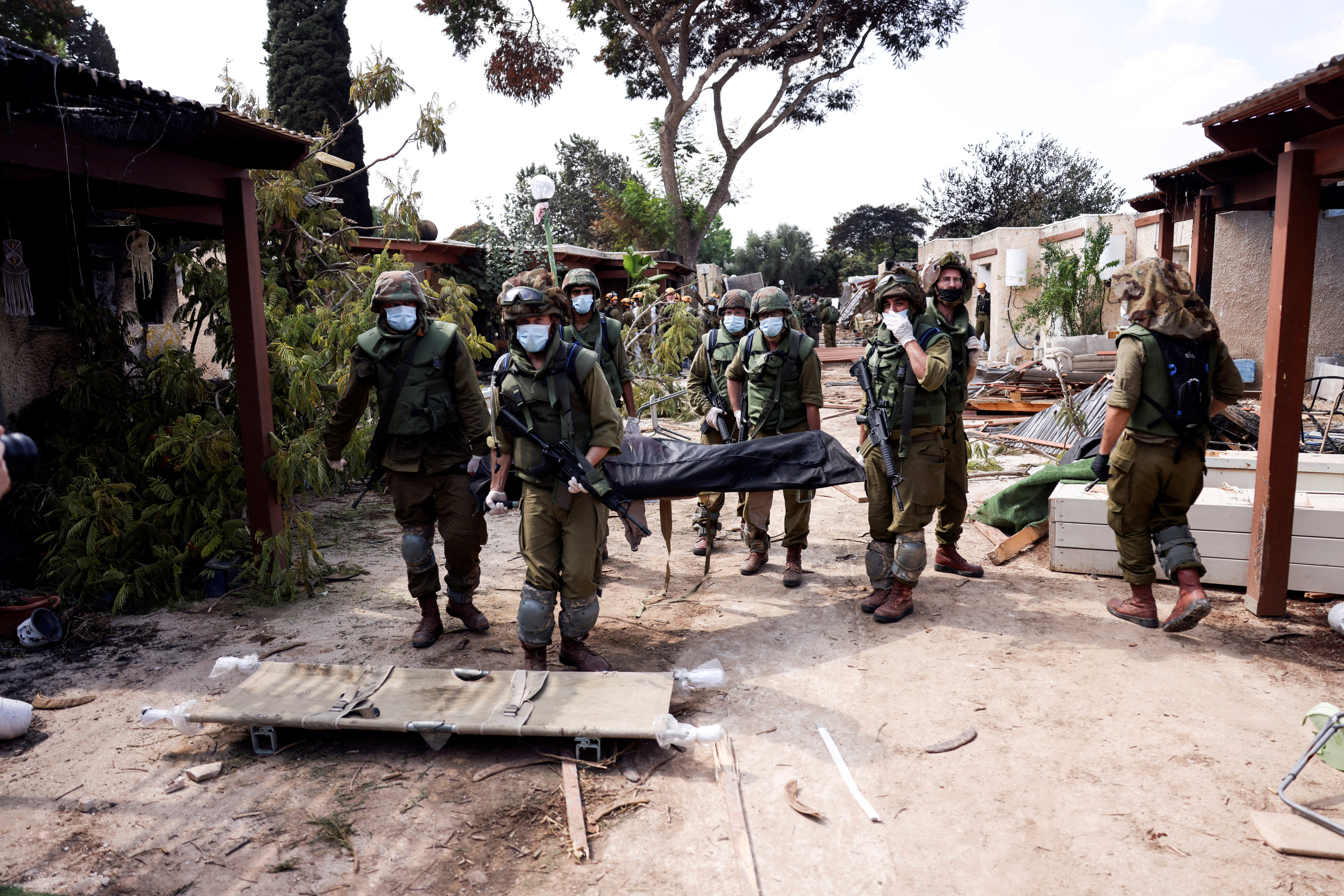 Israeli soldiers carry the body of a victim at Kibbutz Kfar Aza on October 10, 2023. Photo: Reuters