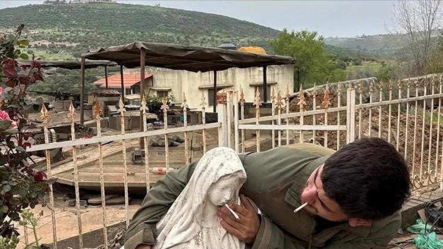 An IDF soldier appearing to put a cigarette in the mouth of a statue of the Virgin Mary. Photo: Reuters