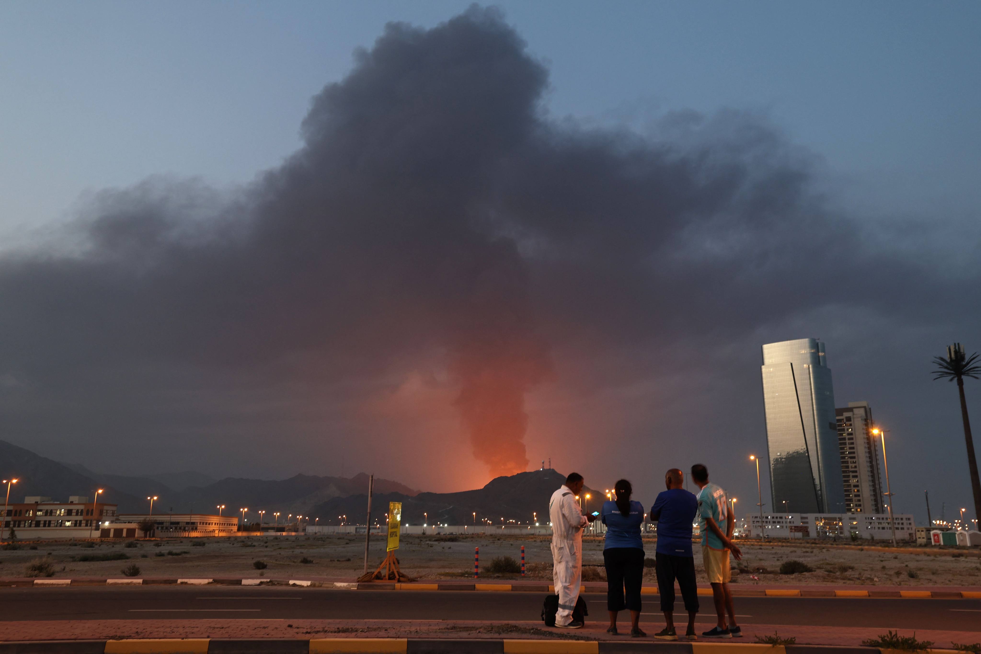 Foreign workers look at a tall plume of black smoke after an explosion in the Fujairah industrial zone in the UAE in March amid the Iran war. Photo: AFP