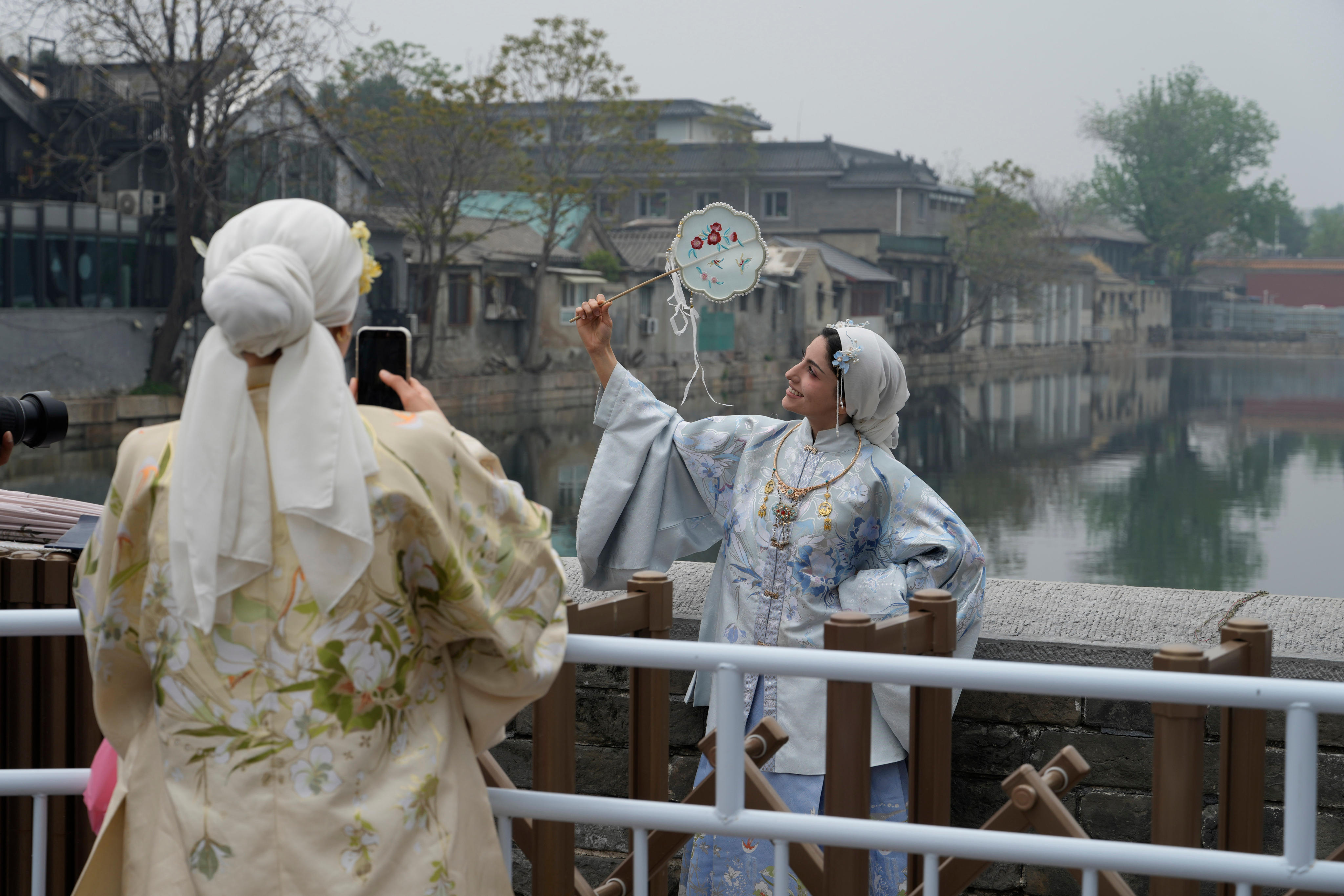 Foreign tourists in traditional Chinese costumes take photos near the Forbidden City in Beijing on April 16. Photo: AP