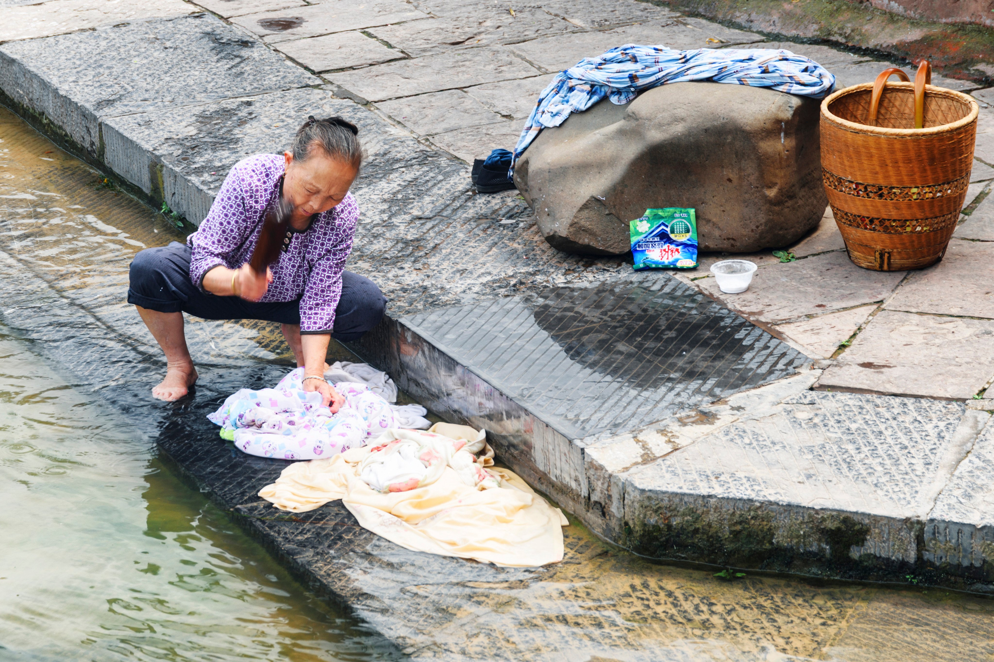 An elderly woman washes clothes the old-fashioned way in a river in Fenghuang Ancient Town in China’s Hunan province. Before the advent of washing machines and chemical detergents, laundry was a labour-intensive affair shaped by local environments and available materials, with clothes typically washed in rivers or streams. Photo: Shutterstock
