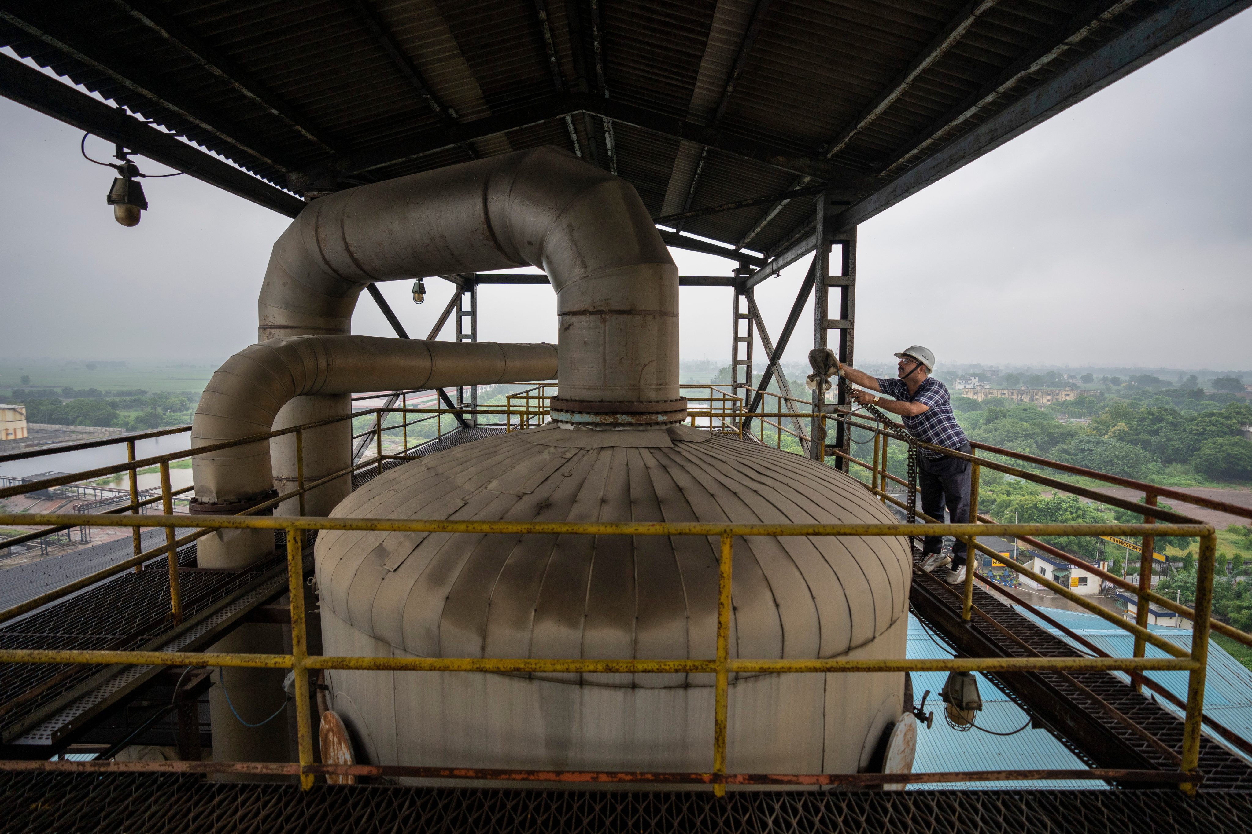 A technician works on the top deck of a distillery at Bajaj Hindustan Sugar factory that produces ethanol in August 2023. Photo: AP