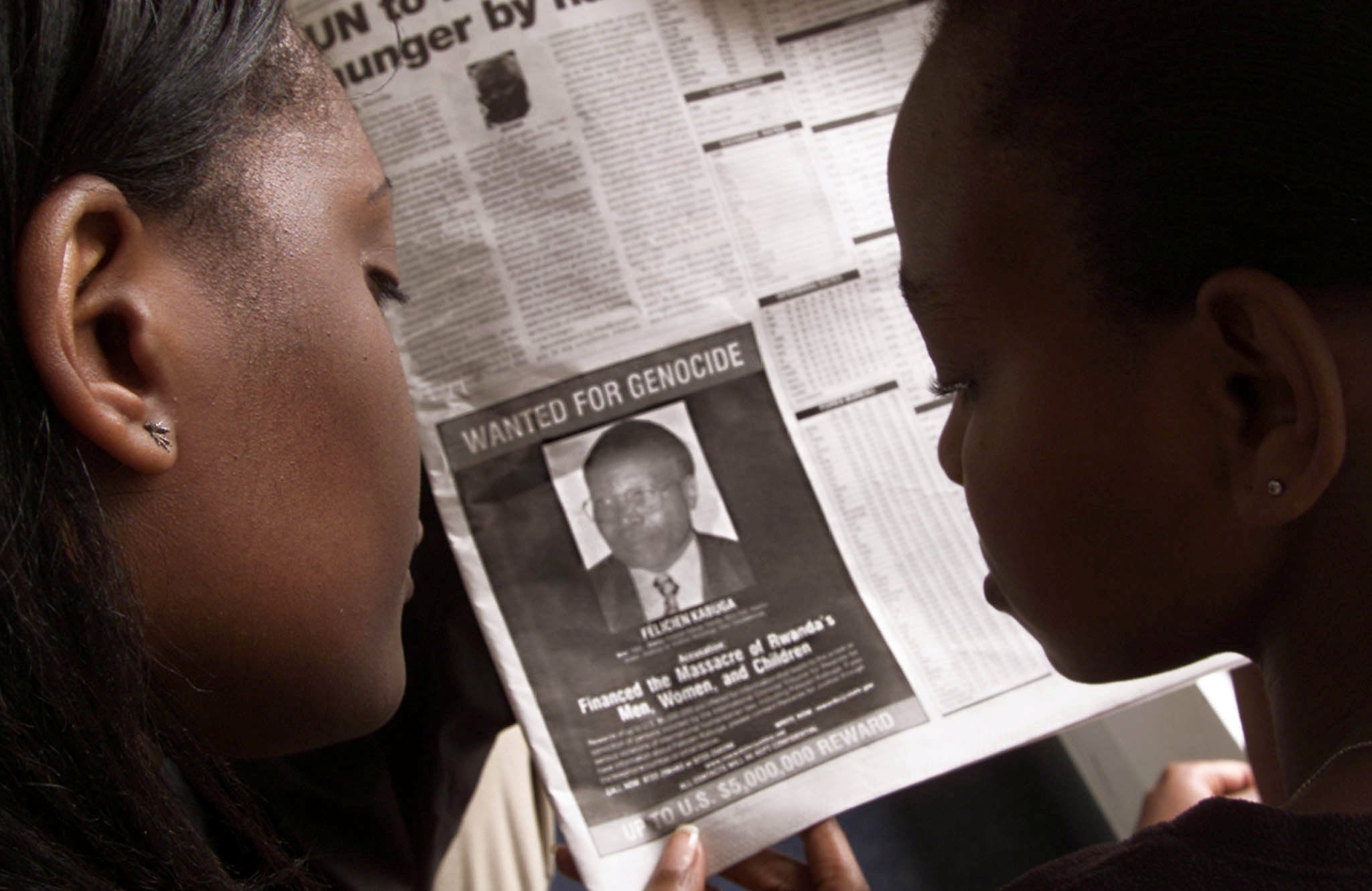 Readers look at a newspaper in Nairobi in June 2002 carrying the photograph of Felicien Kabuga. Photo: Reuters