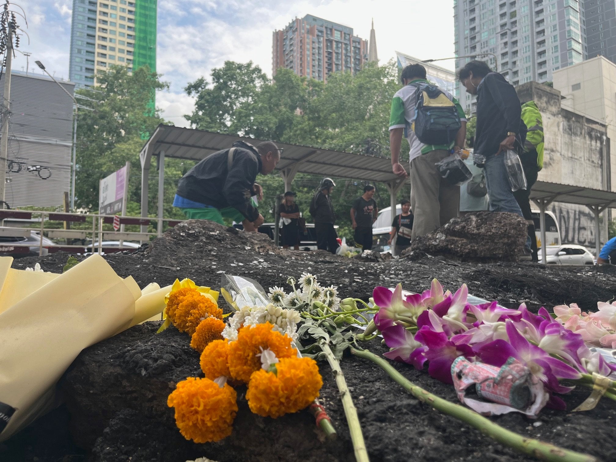 Residents inspect the site of Saturday’s deadly train crash in Bangkok where flowers have been laid in memory of the eight people killed. Photo: Aidan Jones