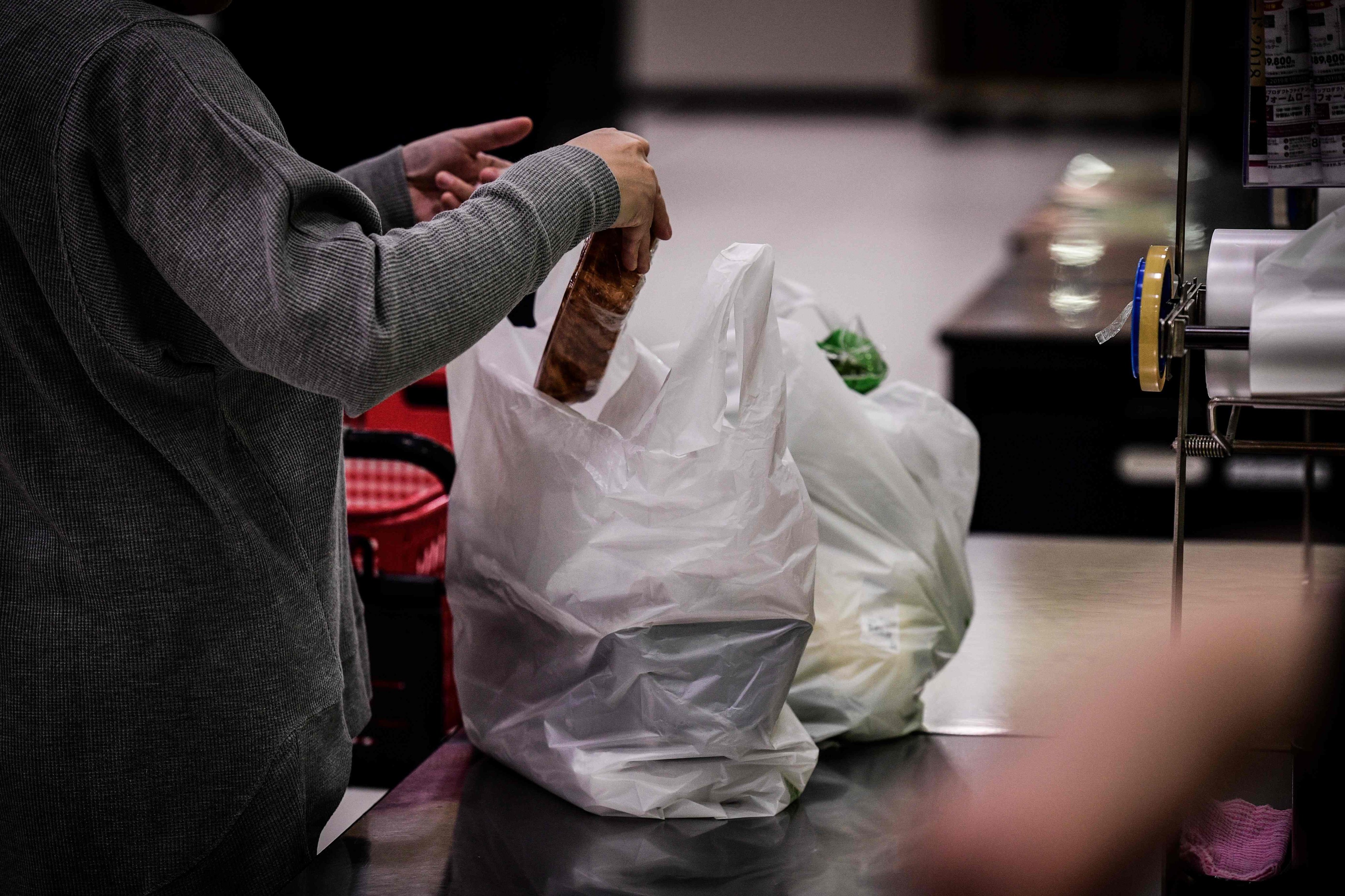 A woman packs her shopping into a plastic bag in a supermarket in Chiba, Japan. Photo: AFP