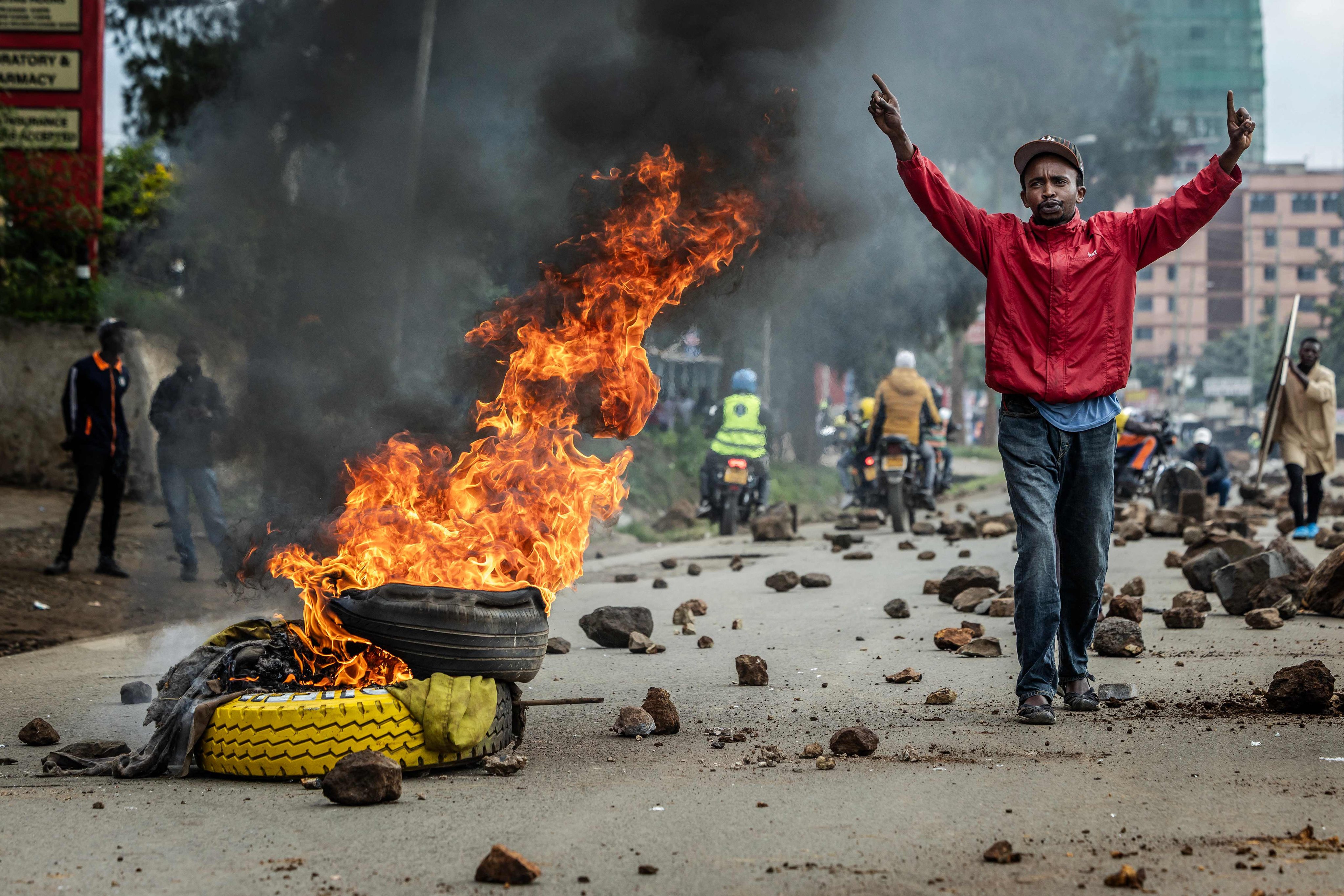 A protester in Nairobi reacts next to a burning barricade on a road blocked with stones to prevent traffic from passing during a nationwide transport strike over rising fuel prices on Monday. Photo: AFP