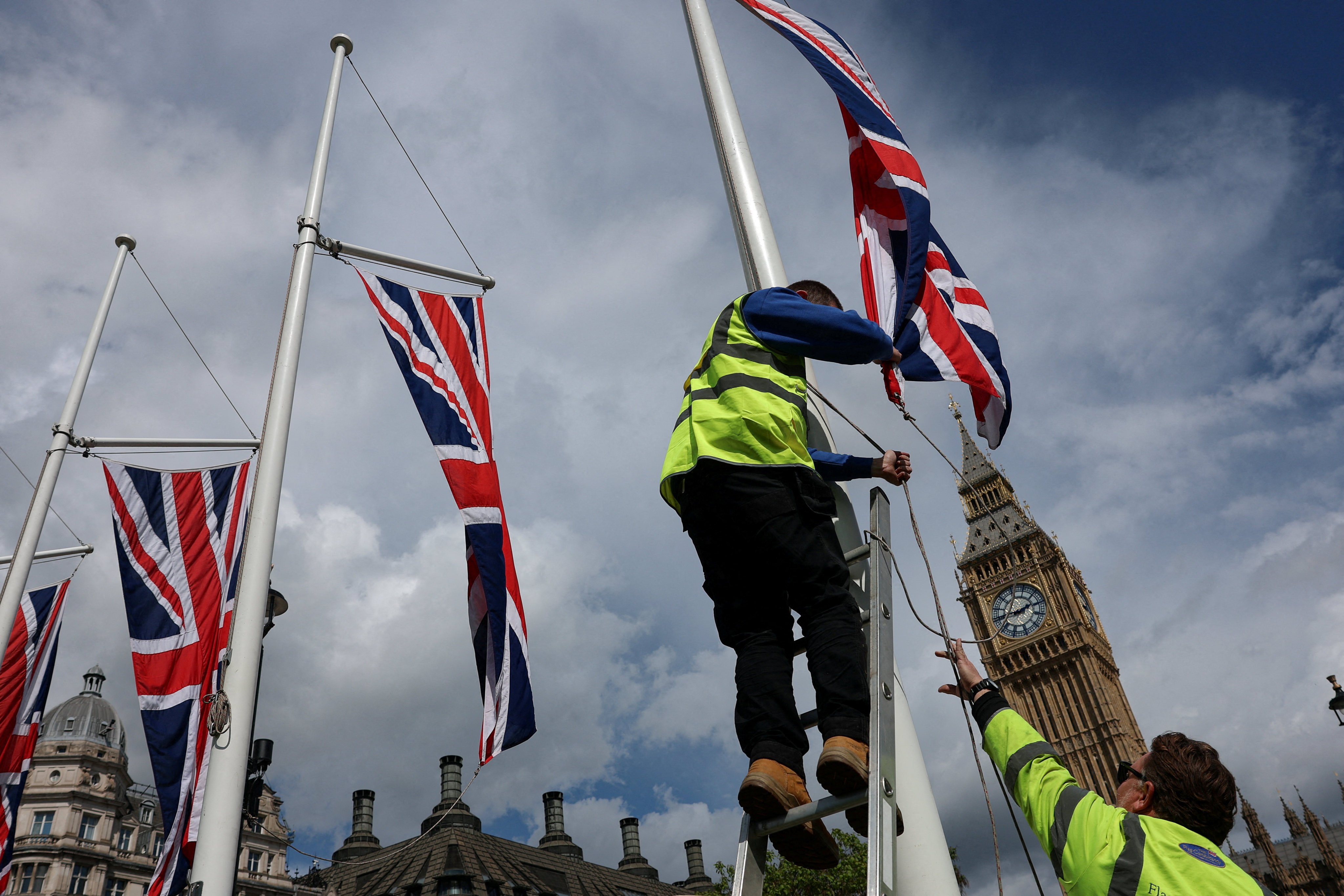 Workers adjust a flag opposite the Elizabeth Tower, commonly known as Big Ben, in London. Photo: Reuters
