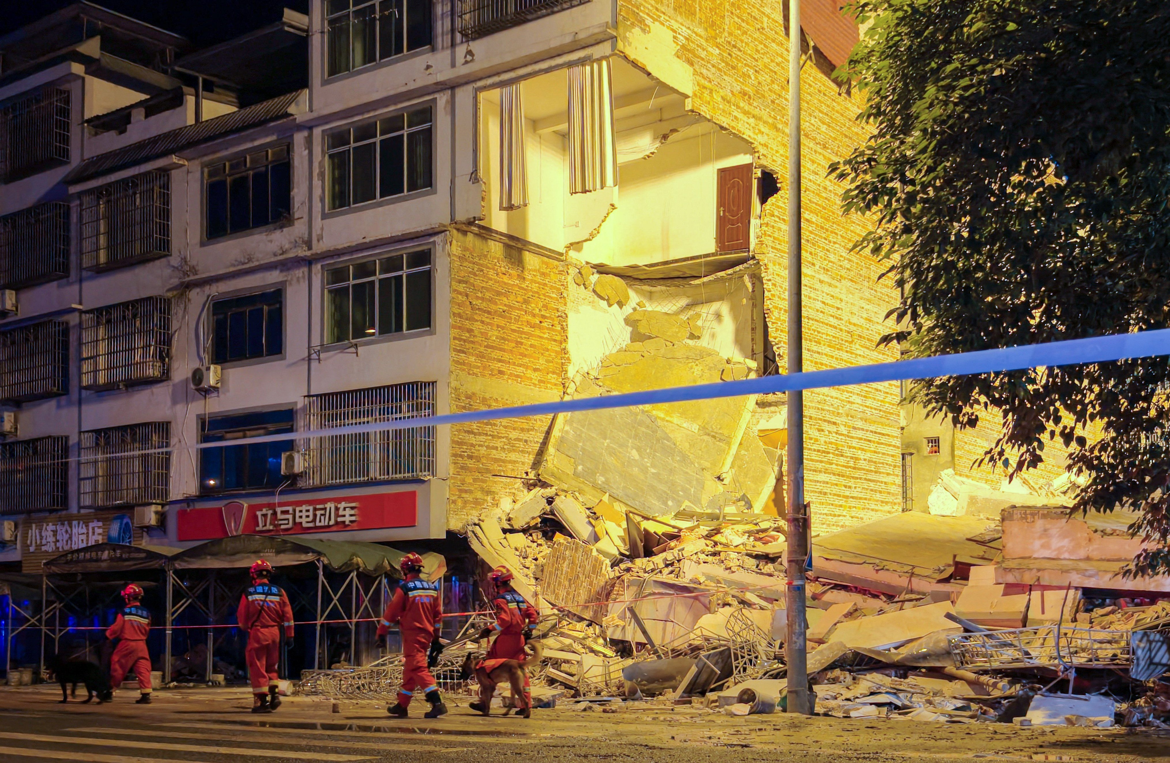 Rescue workers walk past a damaged building following an earthquake in Guangxi. Photo: CNS