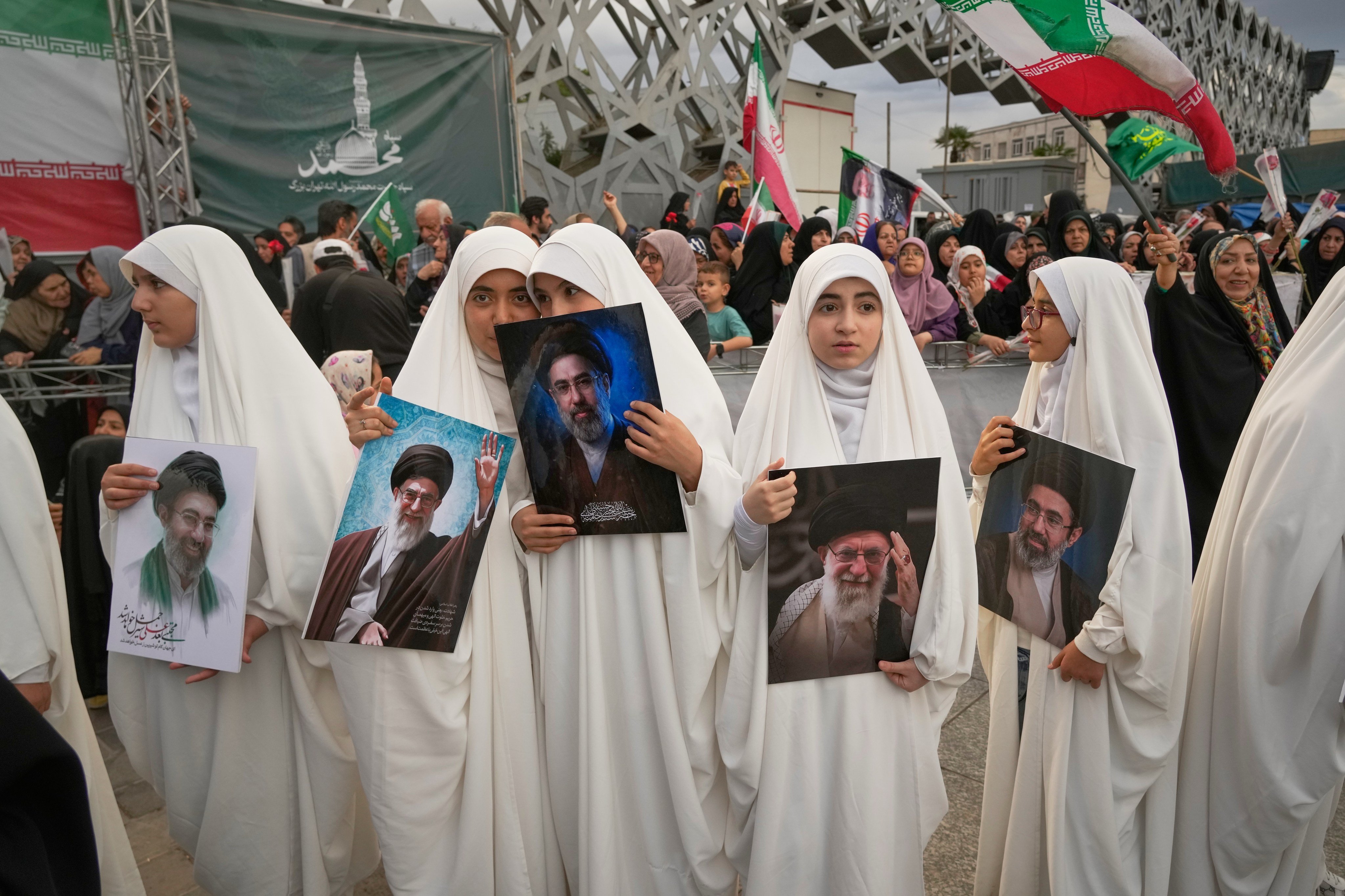 Iranian girls hold portraits of Supreme Leader Ayatollah Mojtaba Khamenei and his late father, Ayatollah Ali Khamenei, as they watch a mass wedding ceremony in Tehran on Monday. Photo: AP