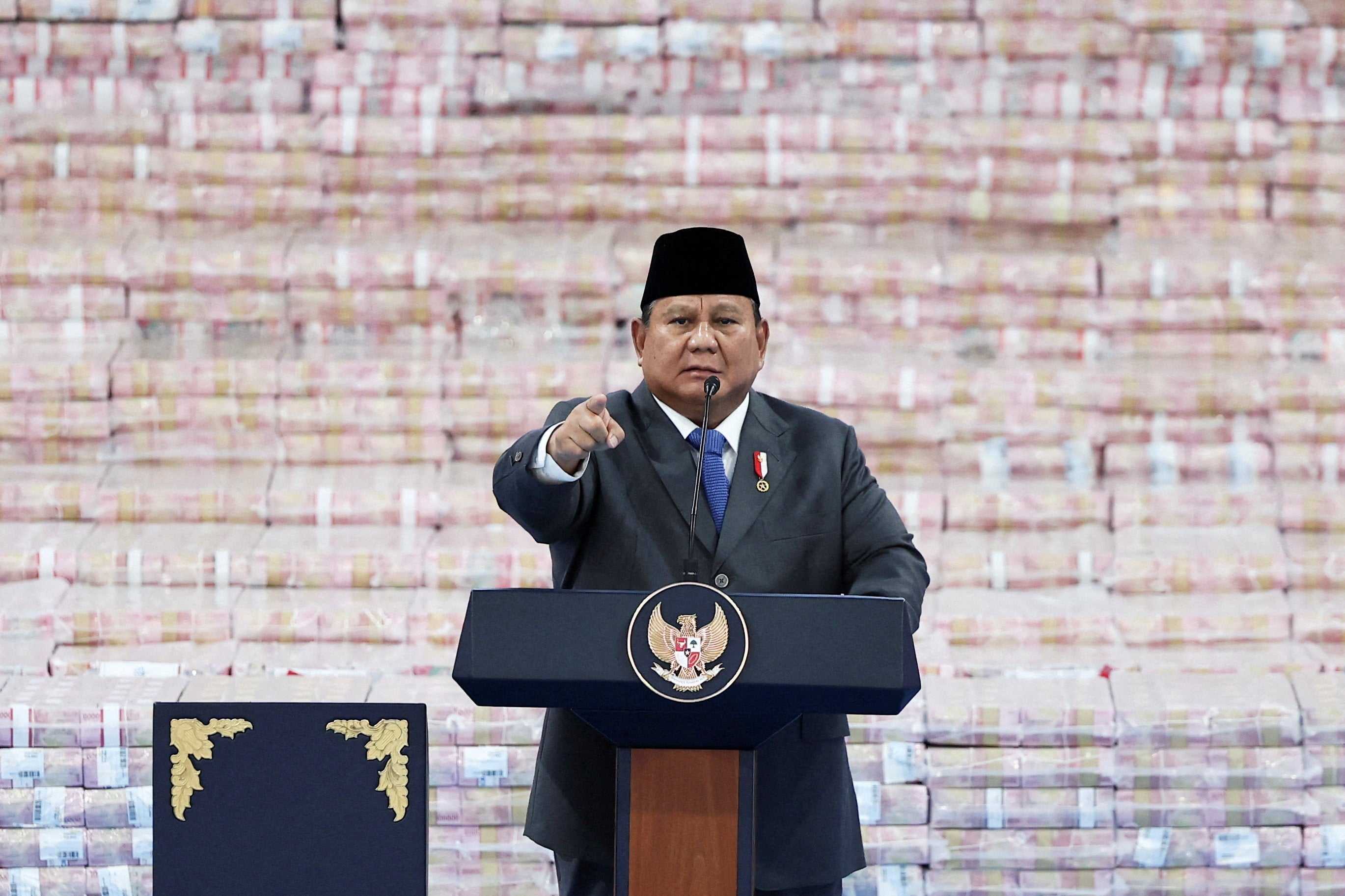 Indonesian President Prabowo Subianto delivers a speech in front of stacks of cash representing the fines paid by companies breaking forestry laws last month. Photo: Reuters