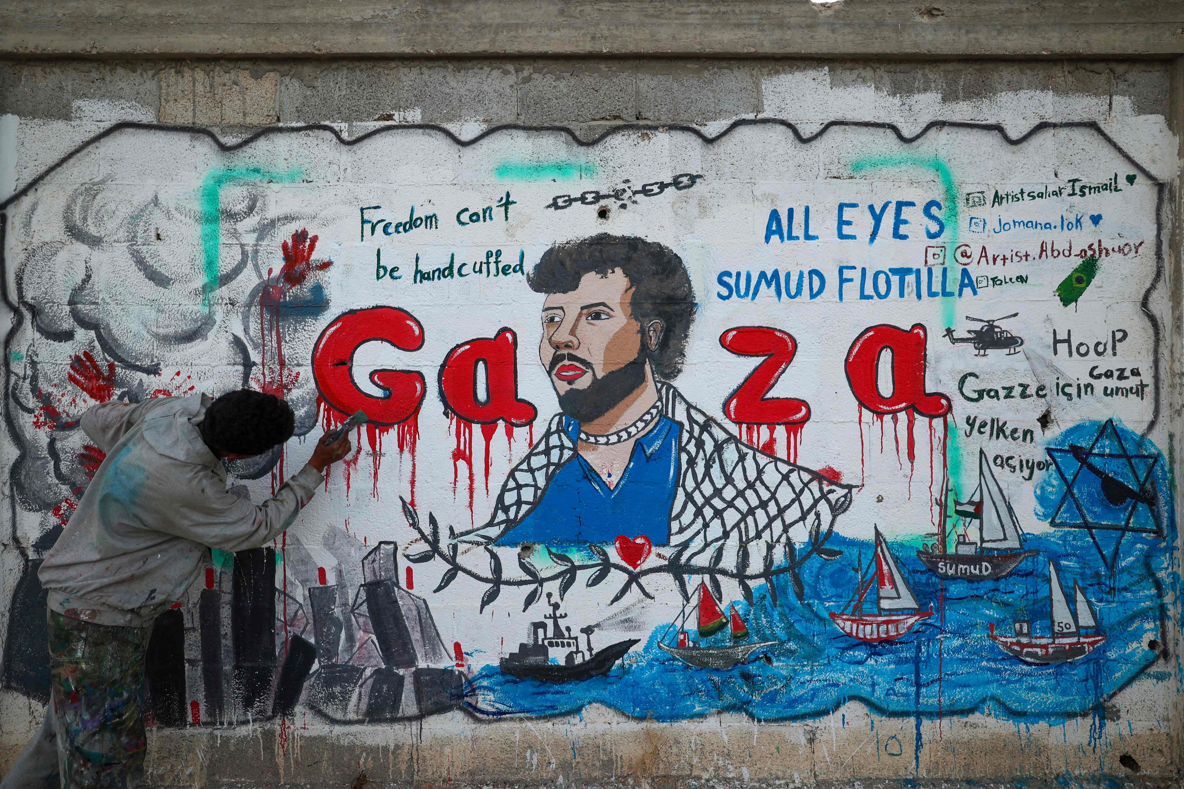 A Palestinian artist paints a mural depicting Israel’s interception of ships participating in the Global Sumud Flotilla, a civilian-led humanitarian aid mission to Gaza by sea, in Nuseirat in the central Gaza Strip on May 19. Photo: AFP