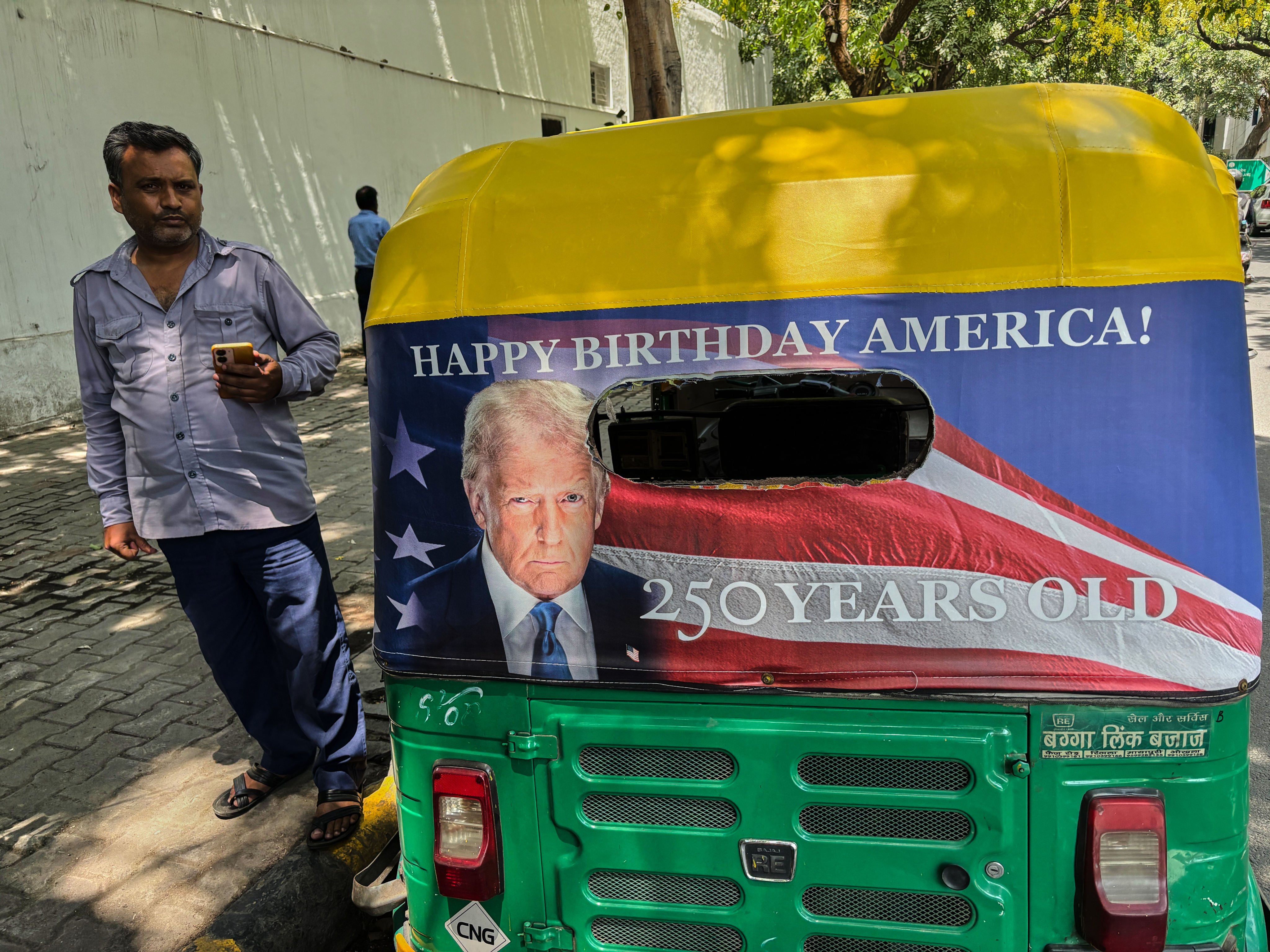 Pradeep Kumar stands next to his autorickshaw featuring a poster of US President Donald Trump in New Delhi on Wednesday. Photo: AP