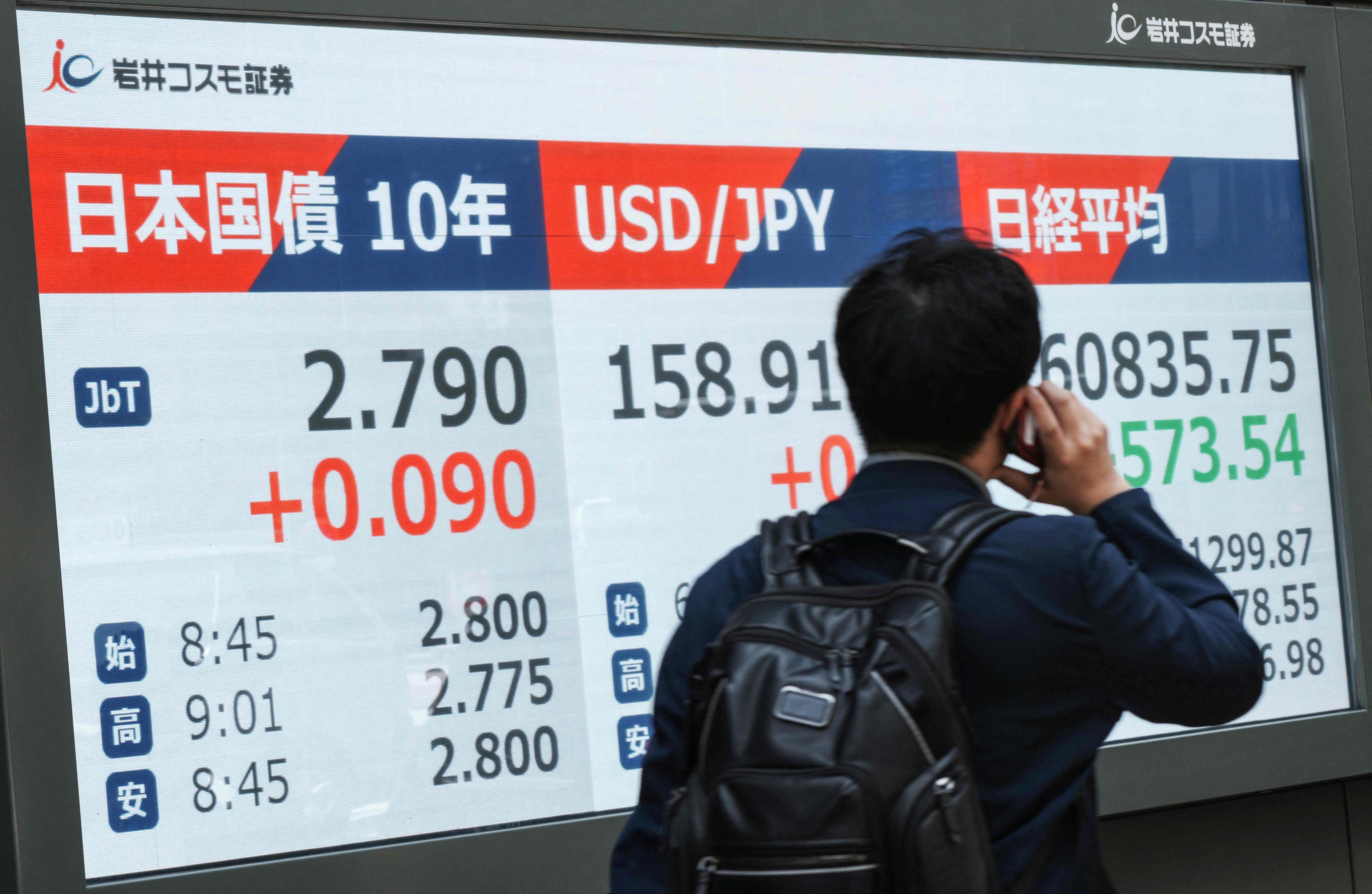 A man walks past an electronic board displaying 10-year Japanese government bonds, an index of long-term interest rates in the Tokyo bond market and the foreign exchange rate of the Japanese yen against the US dollar along a street in Tokyo on May 18. Photo: AFP