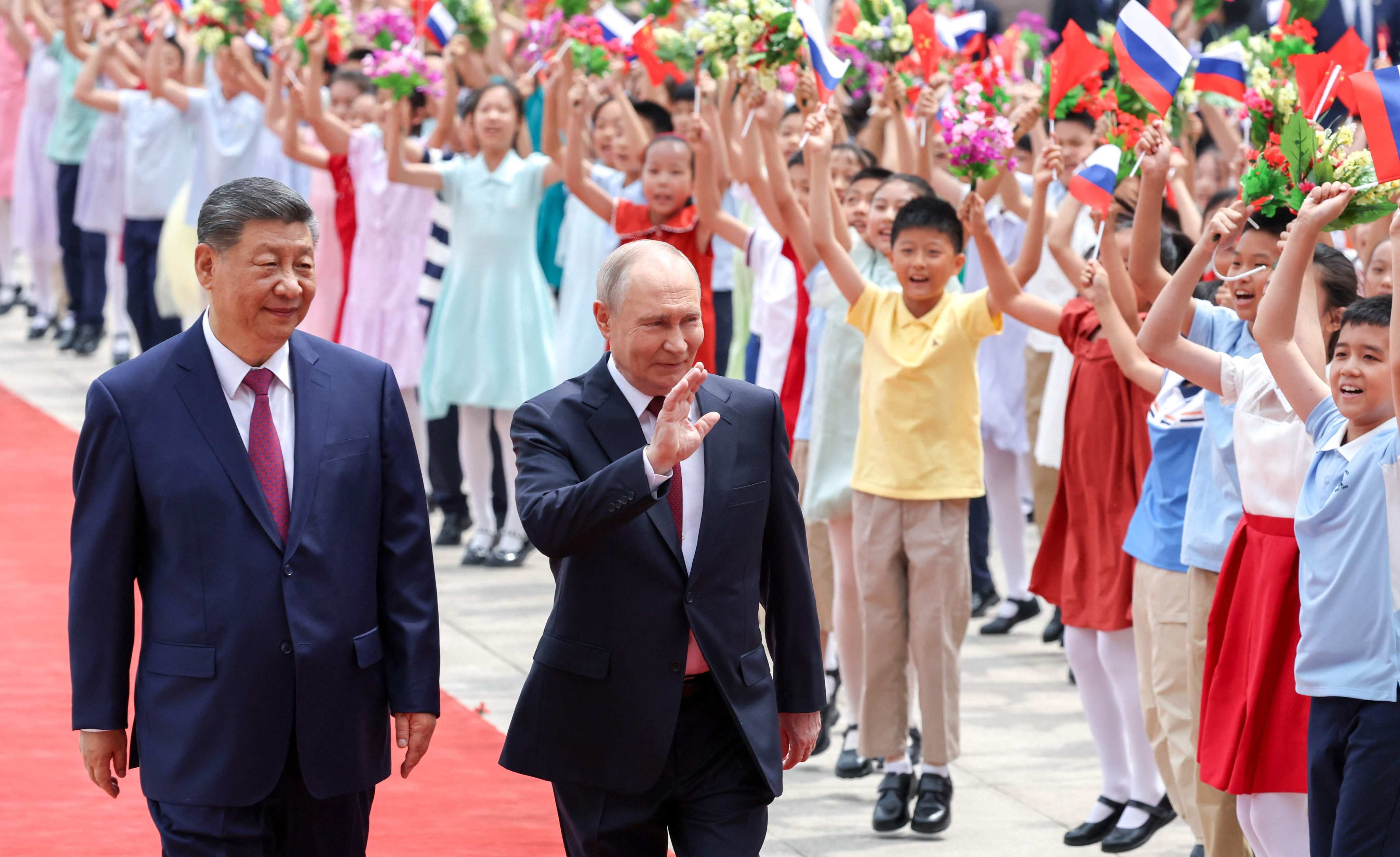 Presidents Xi Jinping and Vladimir Putin wave to a group of children at a welcome ceremony for the Russian leader in Beijing on May 20. Photo: Pool via AFP