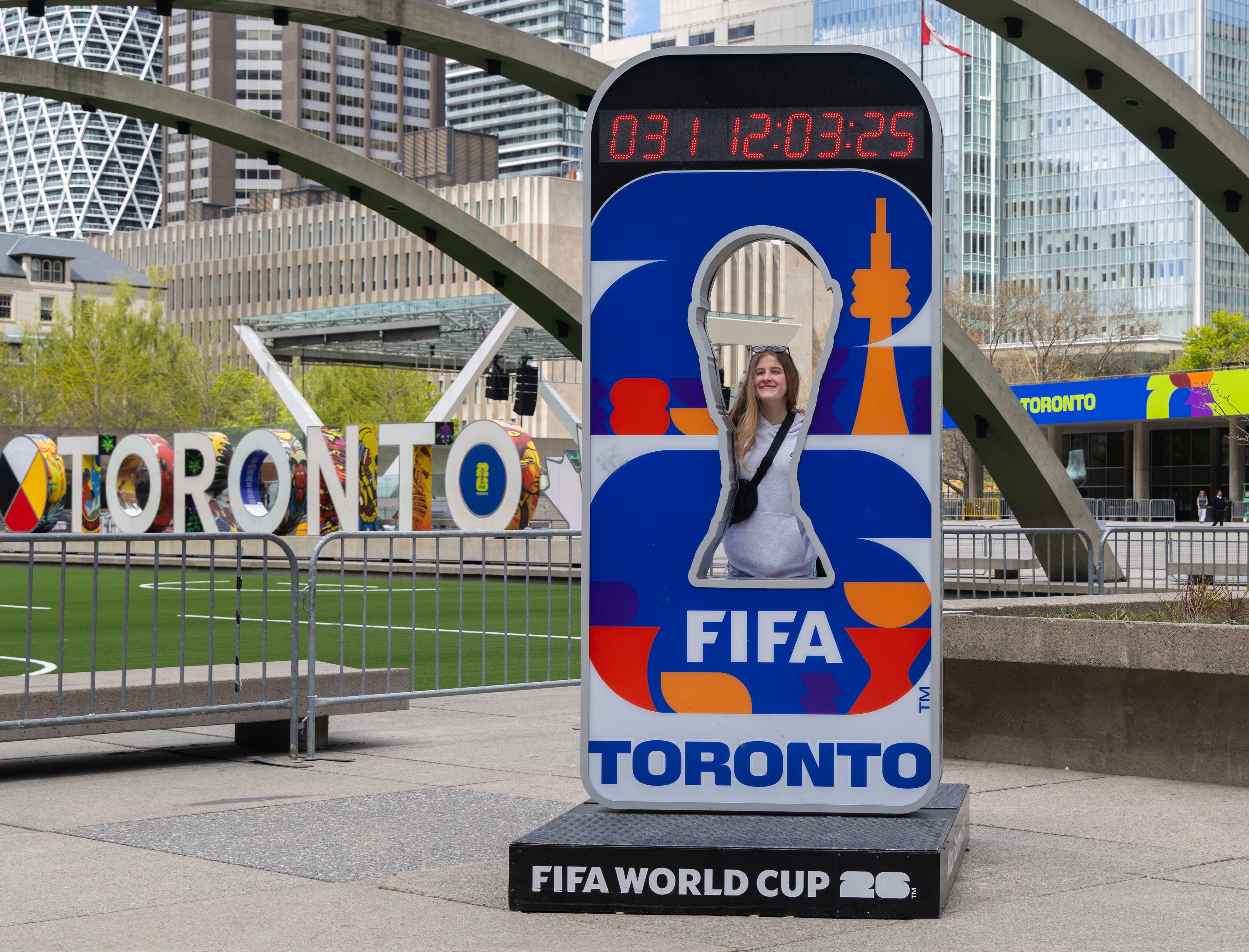 A visitor poses for a photograph with the official Fifa World Cup 2026 Toronto countdown clock at Nathan Phillips Square in Toronto, Canada, on May 11. Photo: Xinhua