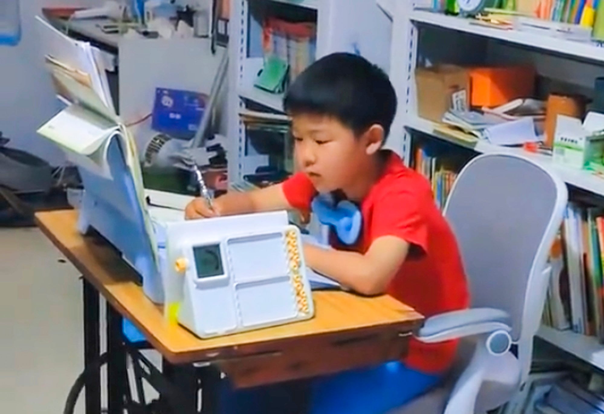 The youngster, above, does his homework as he simultaneously pedals the sewing machine. Photo: Weibo The youngster, above, does his homework as he simultaneously pedals the sewing machine. Photo: Weibo