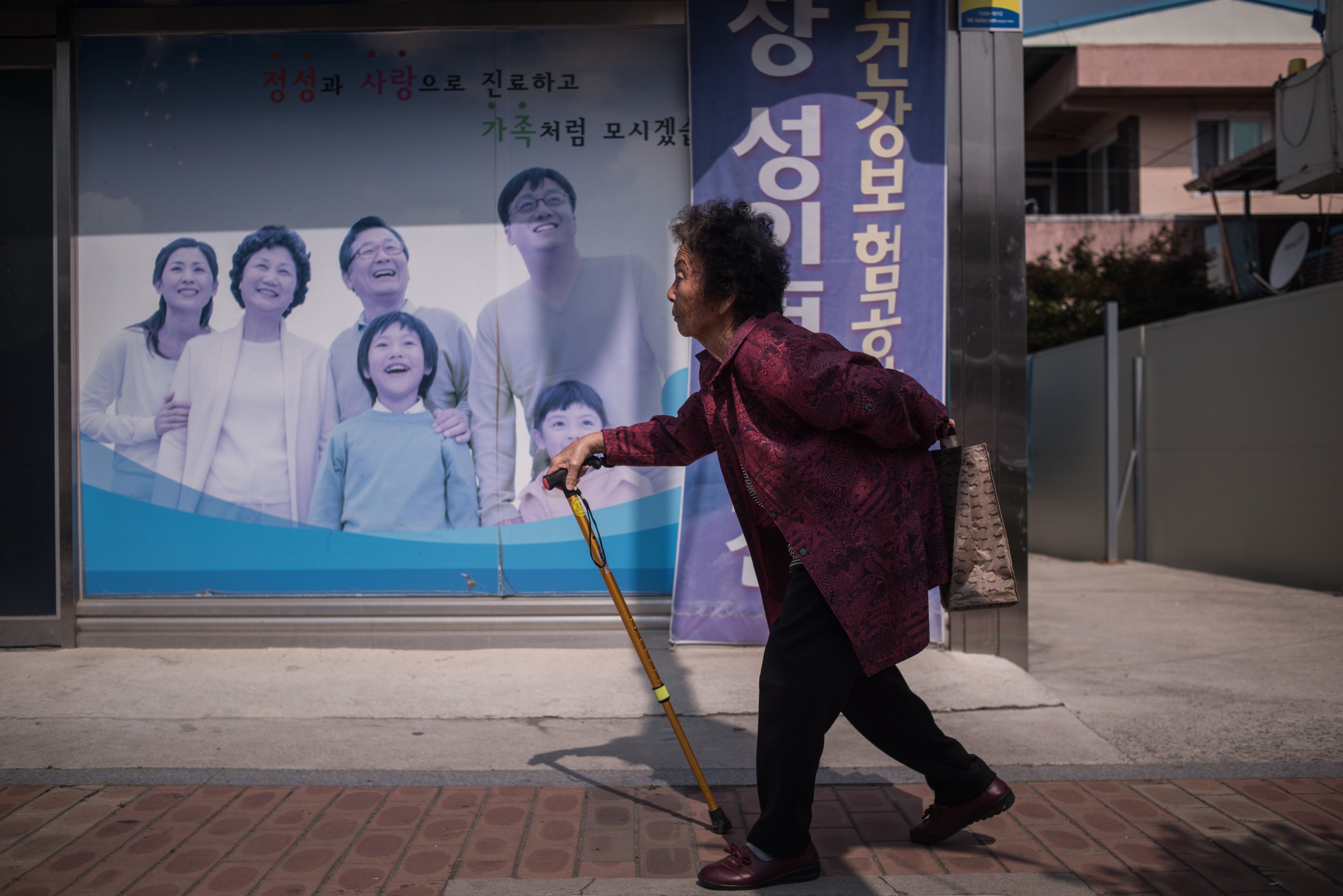 An elderly woman walks past a poster at a health centre in Gunwi, some 200 kilometres south of Seoul, South Korea. The so-called “silver tsunami” poses a major challenge for many of Asia’s big cities, including Hong Kong, one reader writes. Photo: AFP