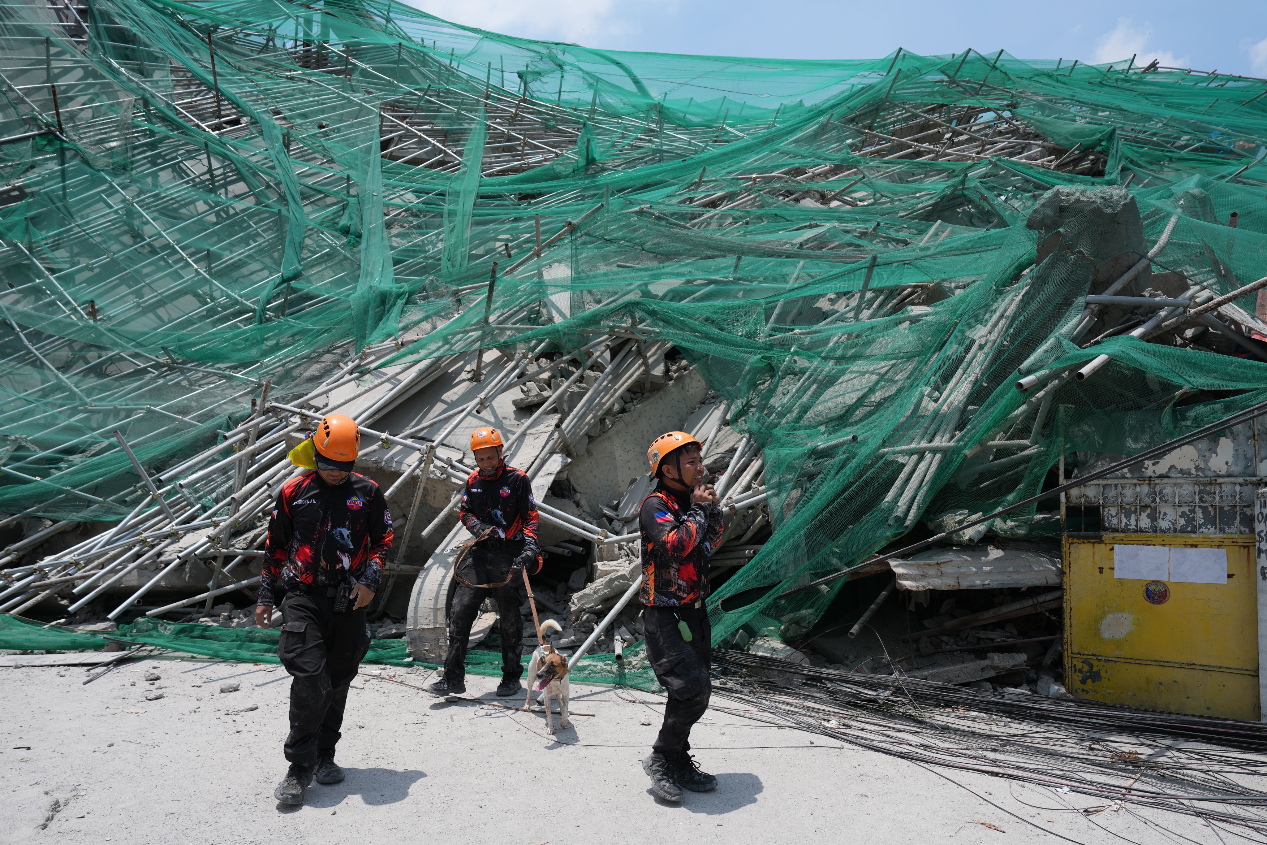 Rescuers and a K-9 dog join search operations of a collapsed building where multiple people are believed to be trapped in Angeles city in Pampanga province, north of Manila, on Monday. Photo: AP