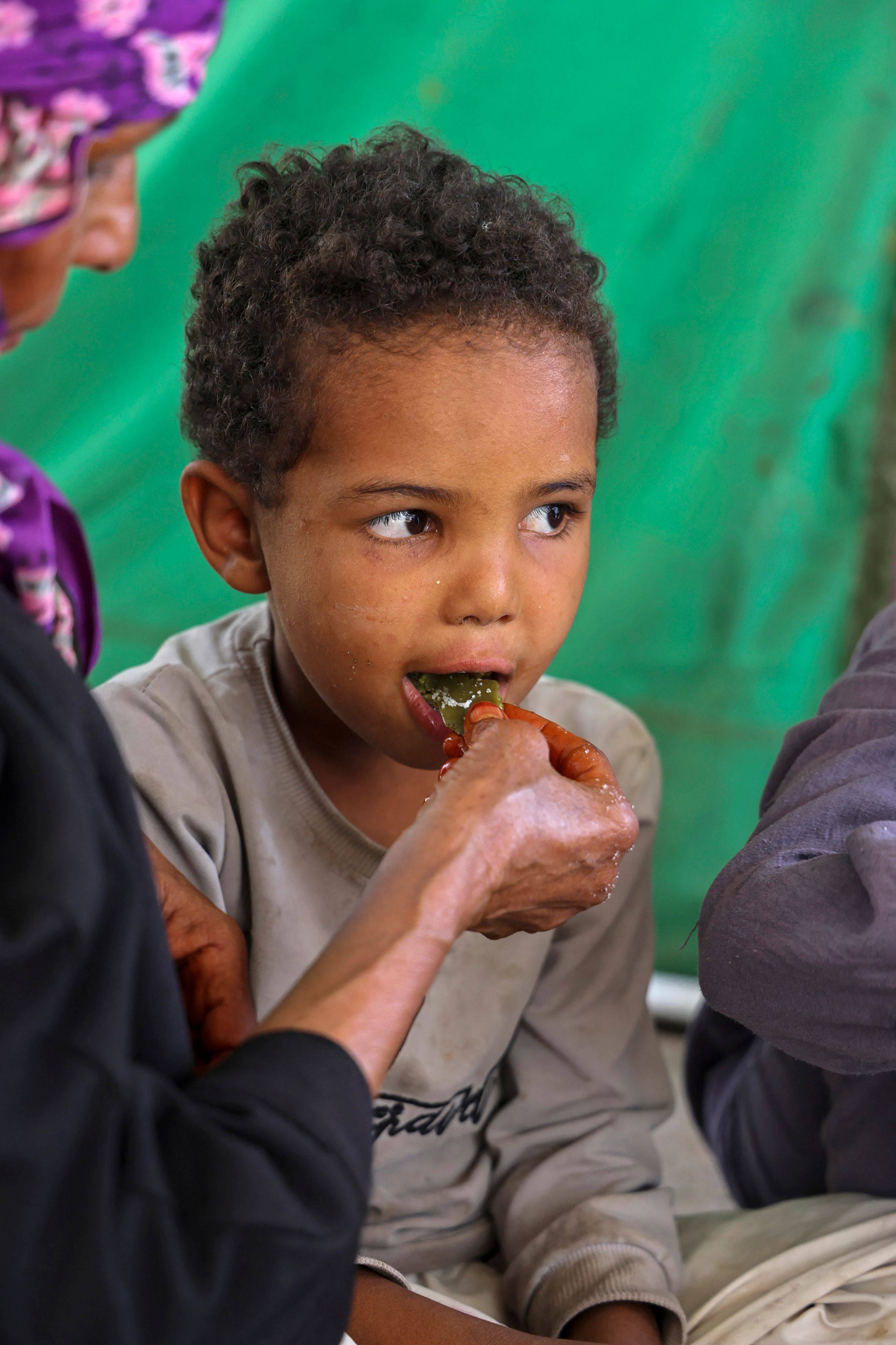 Displaced Yemeni woman Saeedah Mohammed feeds one of her grandchildren with boiled tree leaves. Photo: AFP