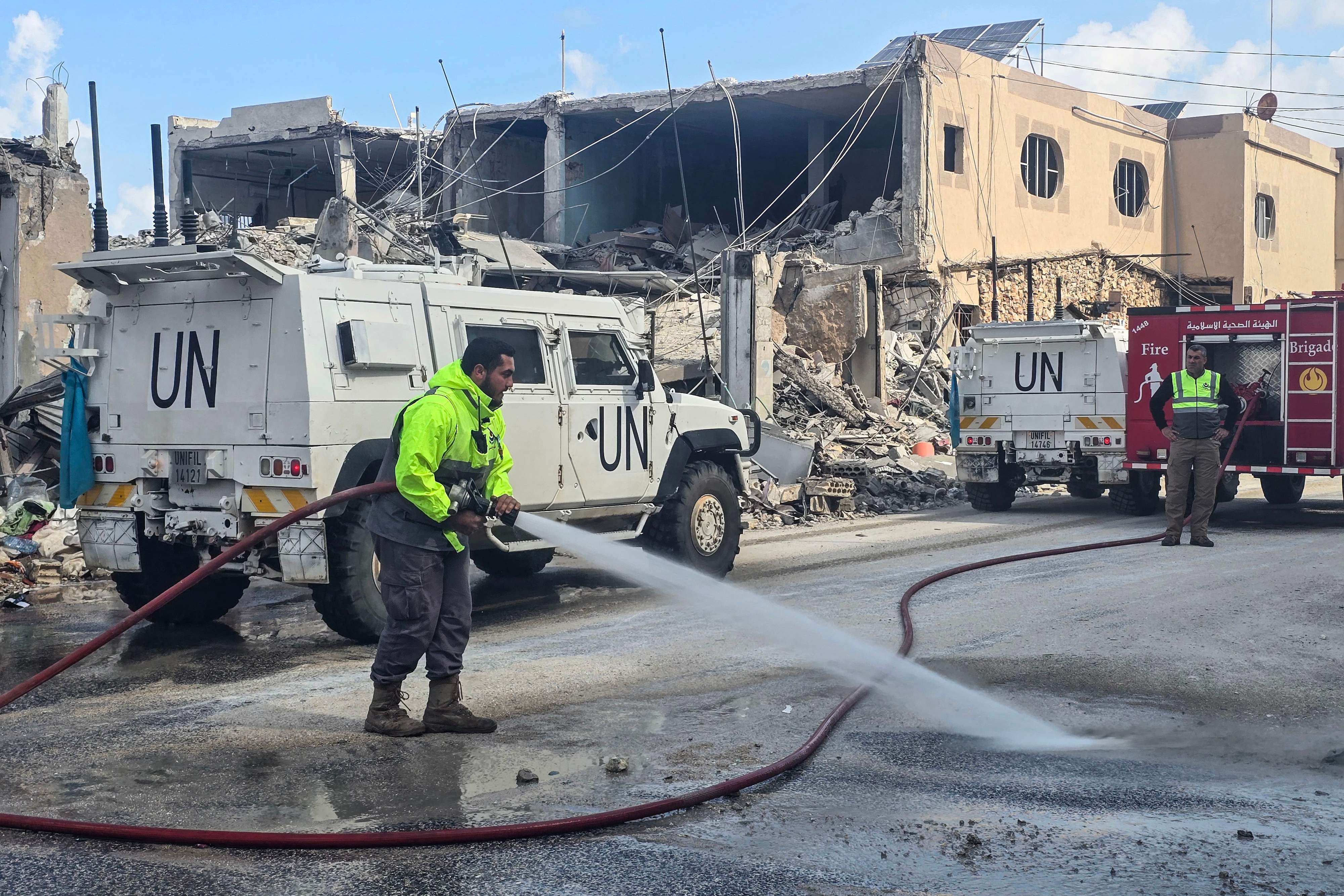 United Nations peacekeepers with the UN Interim Force in Lebanon (UNIFIL) drive past firefighters clearing the road at the site of an overnight Israeli air strike in southern Lebanon in March. Photo: AFP