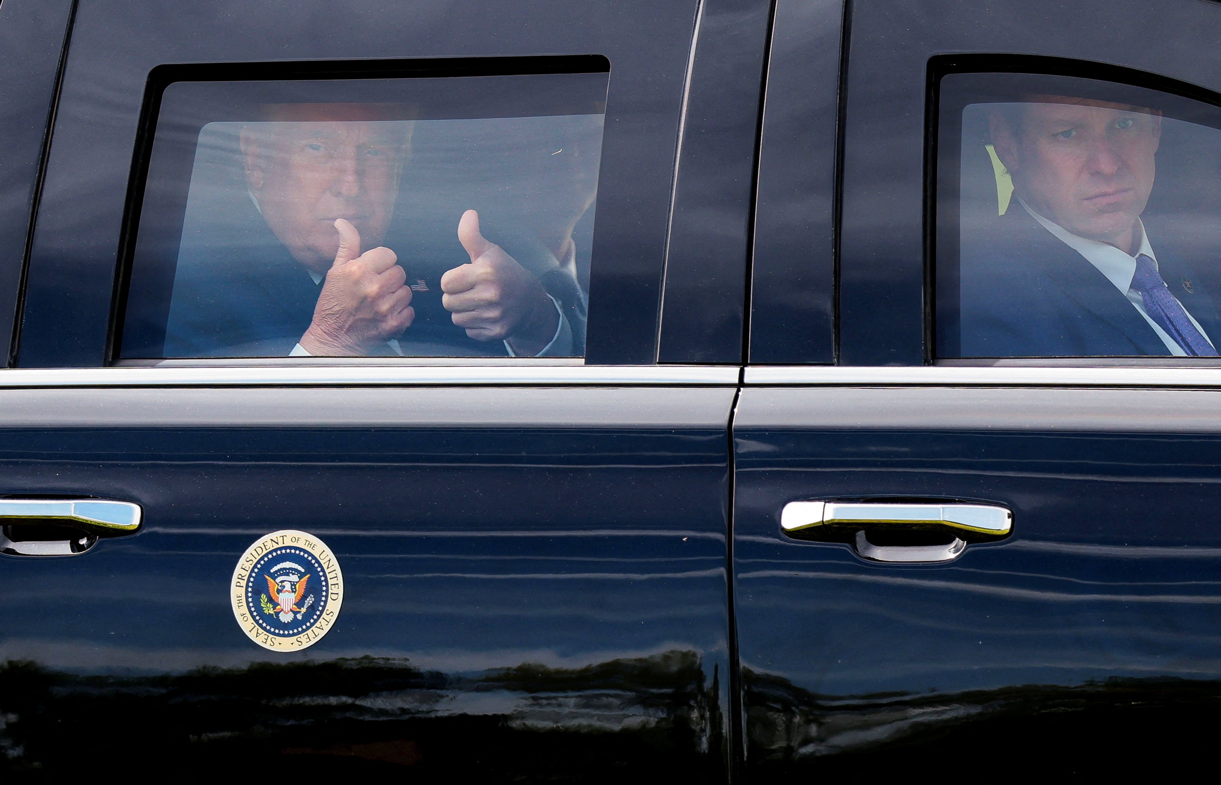 US President Donald Trump gives a double thumbs-up from inside his limousine. Photo: Reuters