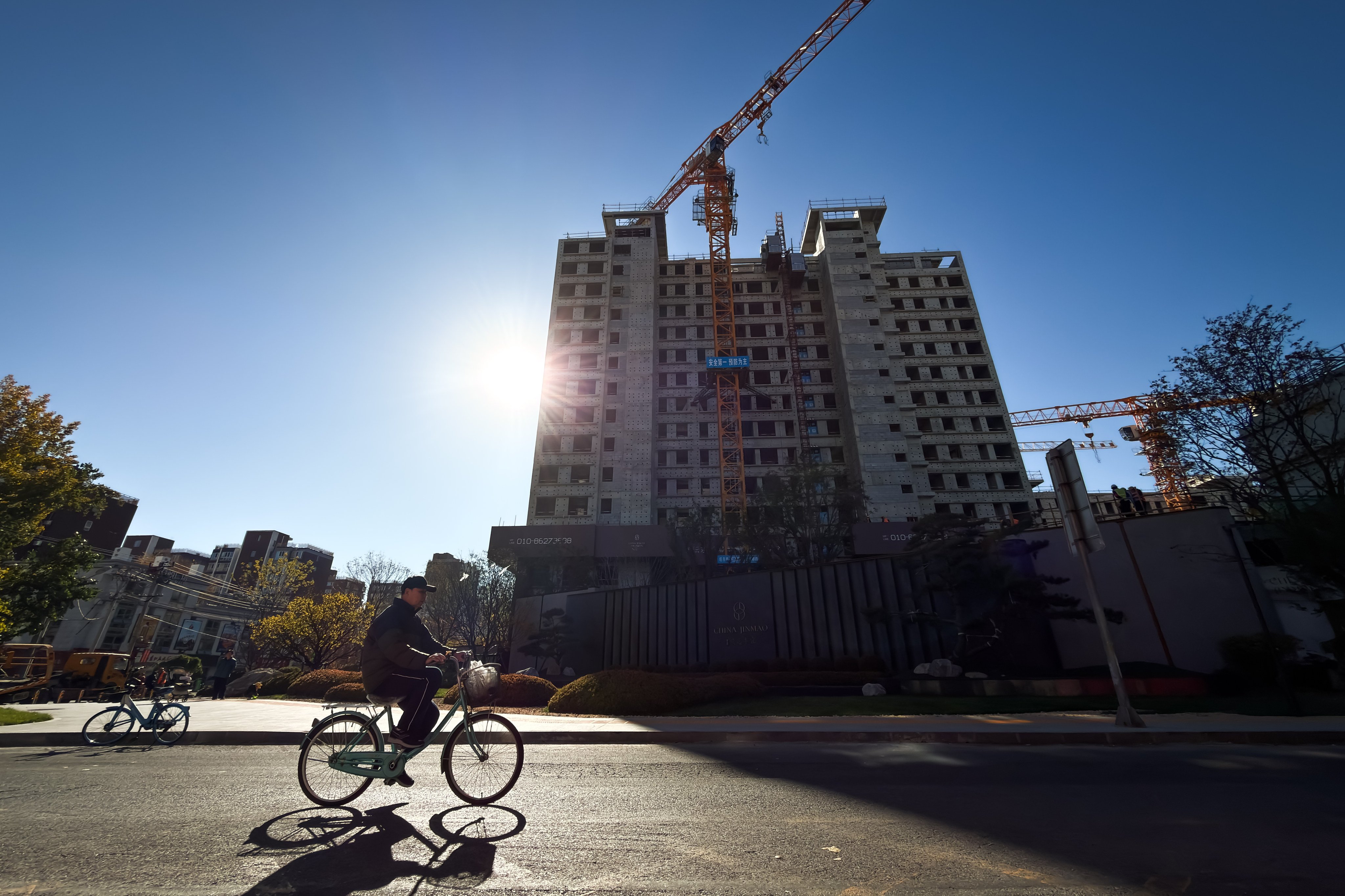 A cyclist rides past a residential construction site in Beijing in November. Photo: Getty Images