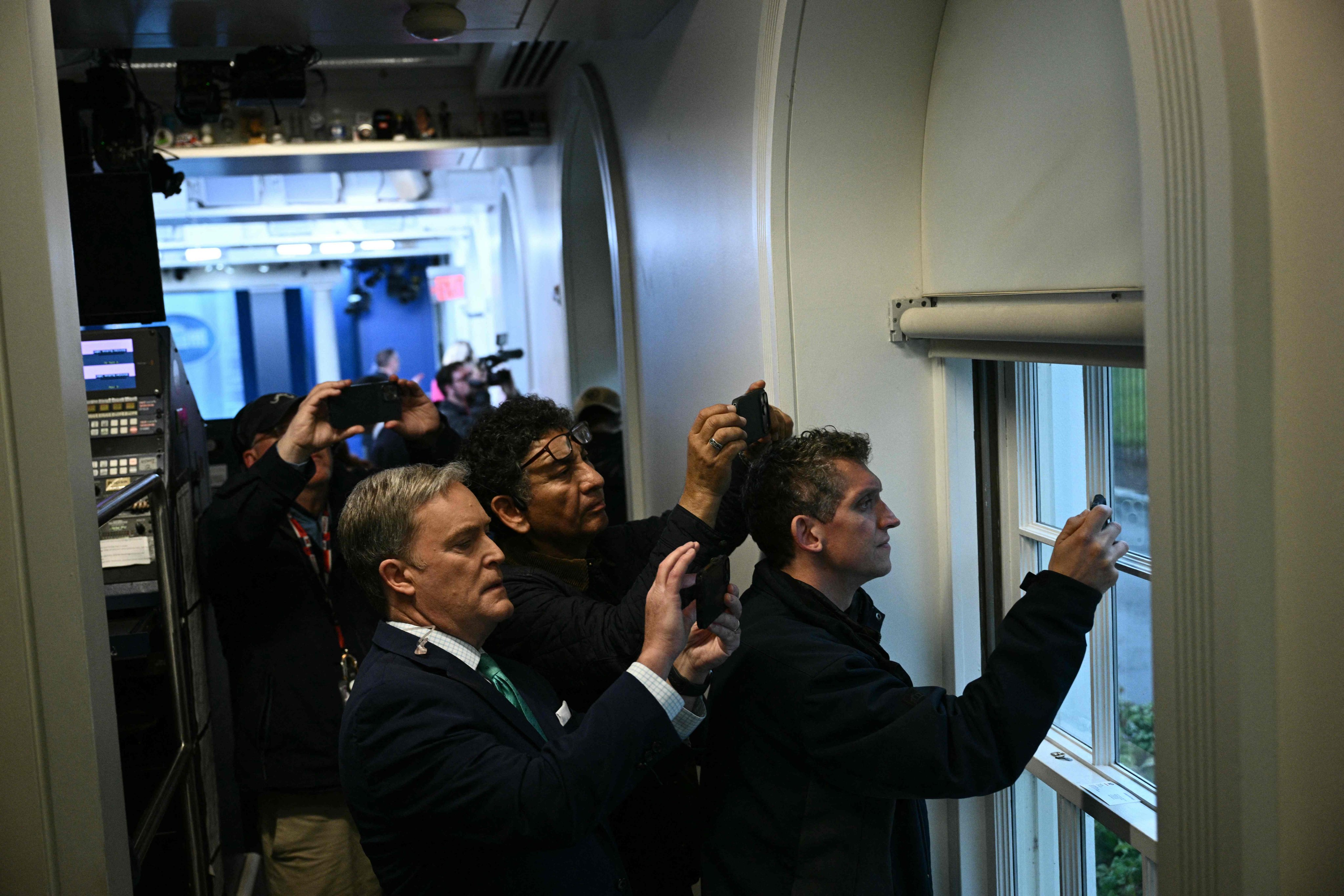 Reporters hold up their phones near a window in the Press Briefing room after a lockdown is triggered by a shooting near  the White House on Saturday. Photo: AFP