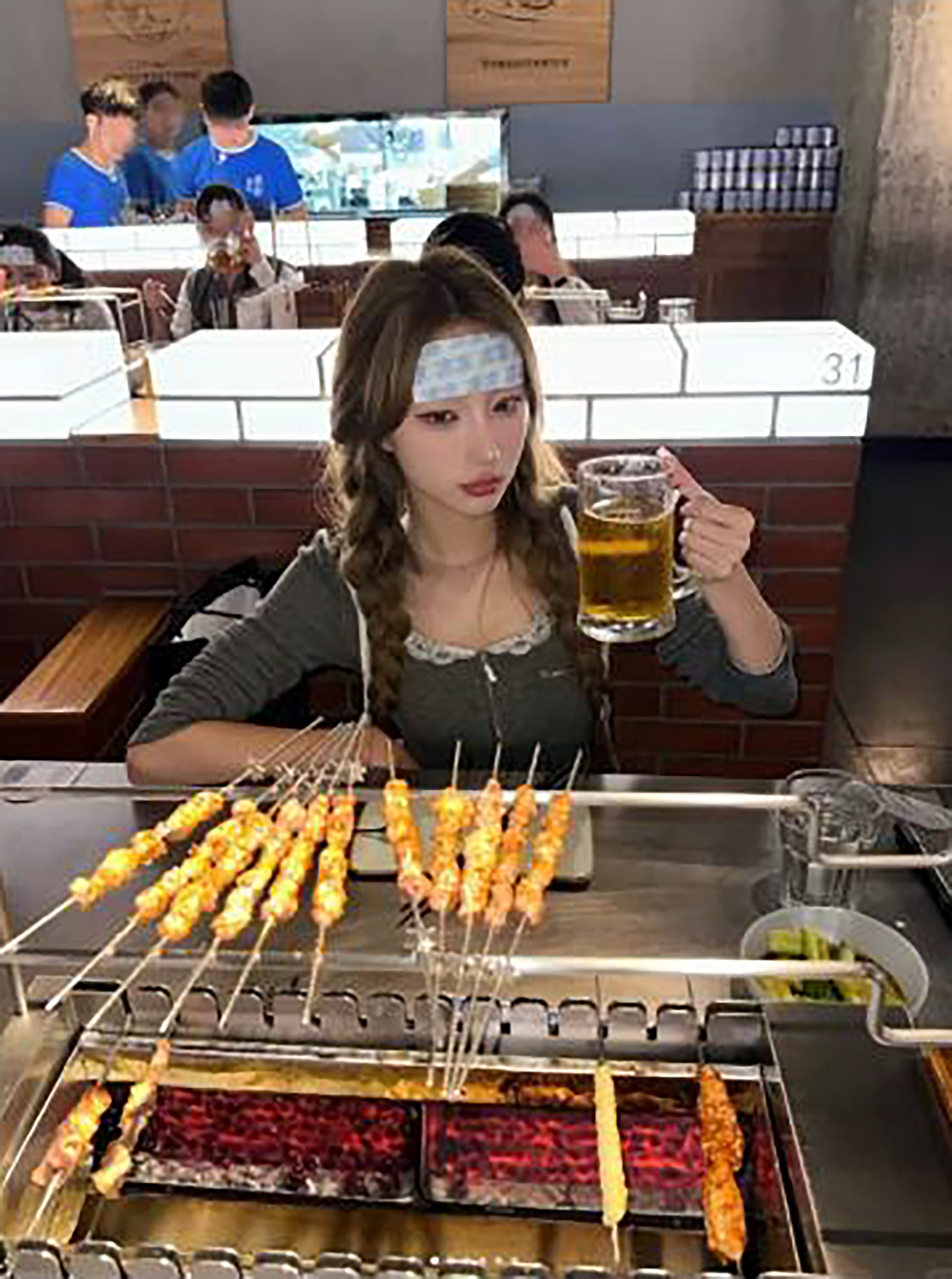 A woman customer, above, enjoys a beer before tucking into some grilled food. Photo: RedNote A woman customer, above, enjoys a beer before tucking into some grilled food. Photo: RedNote