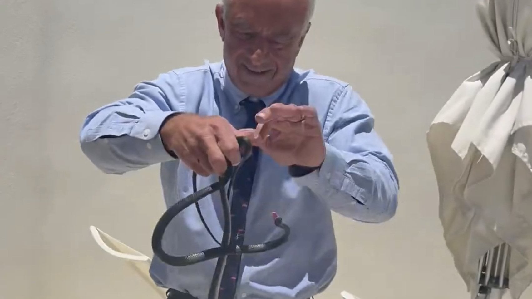 Robert Kennedy Jnr handling two snakes as one of them tries to bite him. Photo: @RobertKennedyJr via X